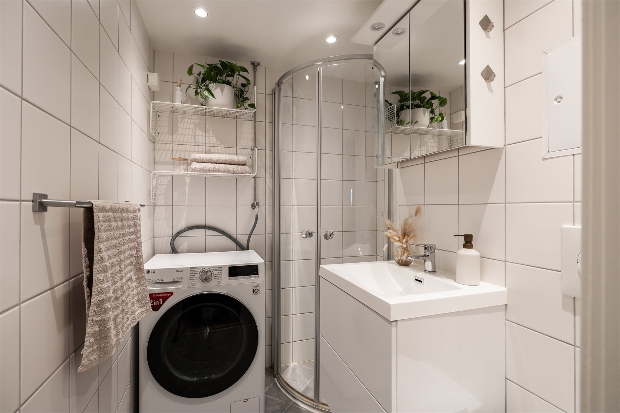 Badet er flislagt og har innredning med servant, vegghengt toalett og dusjhjørne med innfellbare dører.