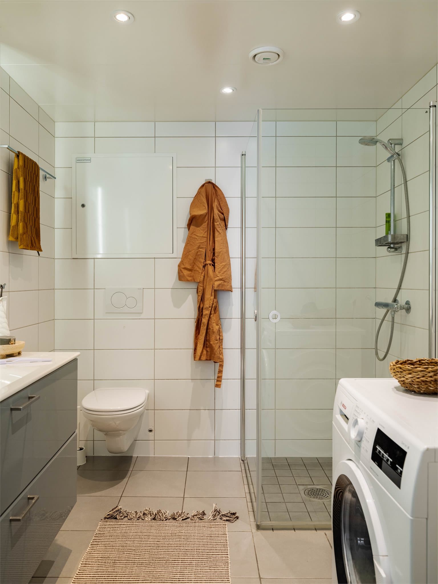 Et flislagt baderom med opplegg for vaskemaskin.