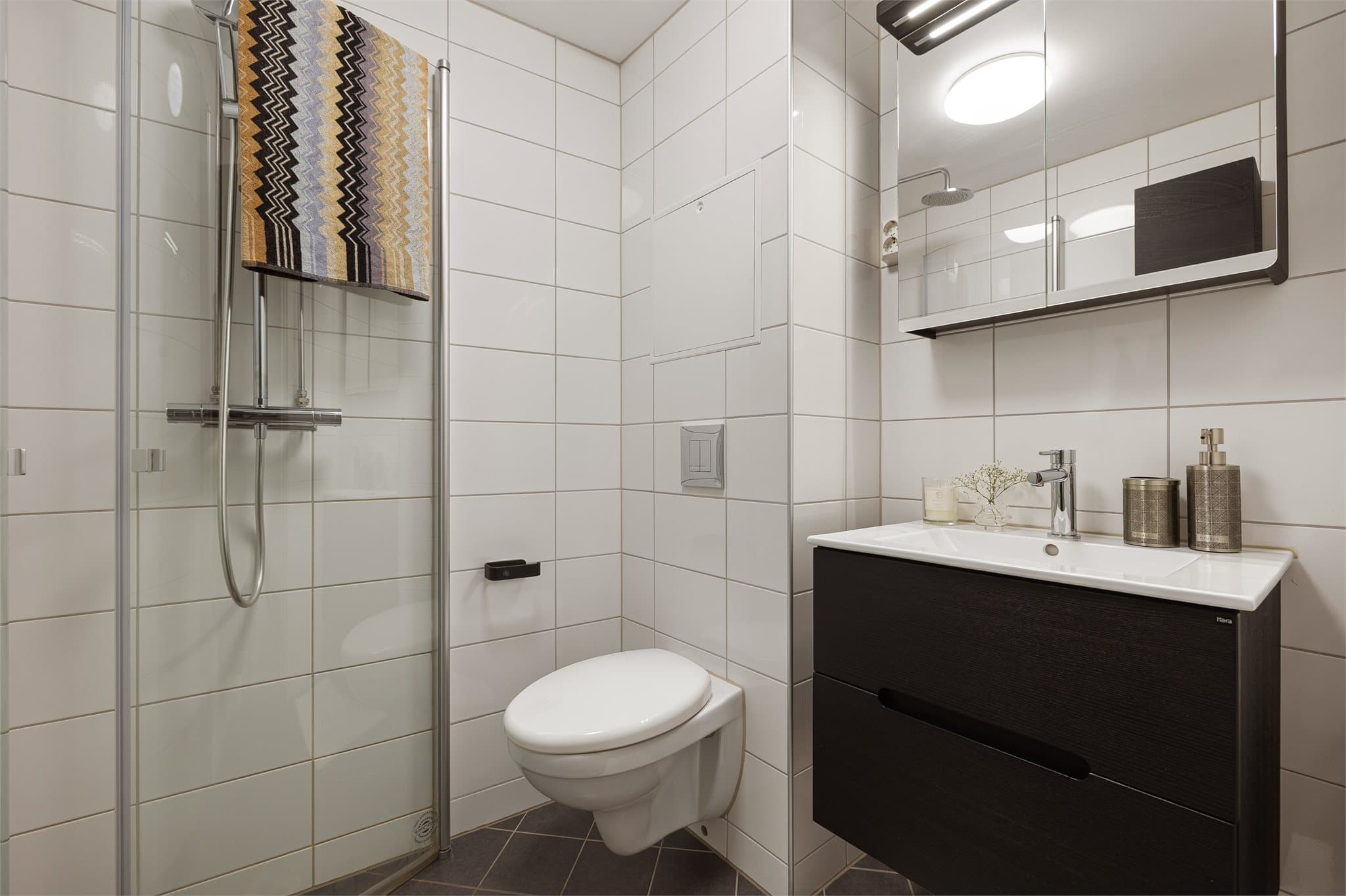 Badet ble renovert i 2018 og fremstår pent og moderne. Her finner du dusjhjørne, toalett, vegghengt servantinnredning, høyskap samt speil med belysning.