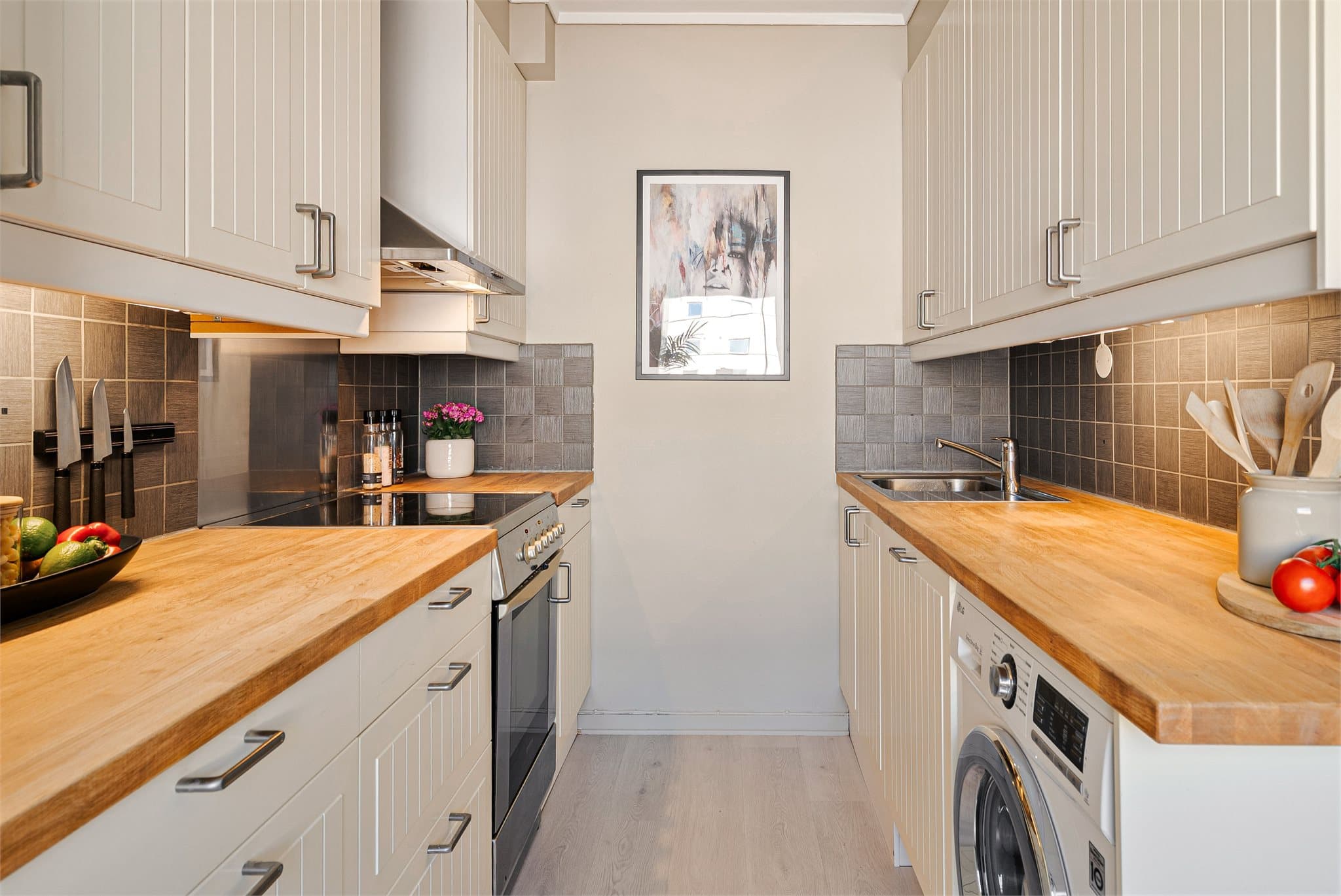 Et lyst og tidløst kjøkken med hvite fronter og benkeplate i tre gir et varmt og innbydende uttrykk.