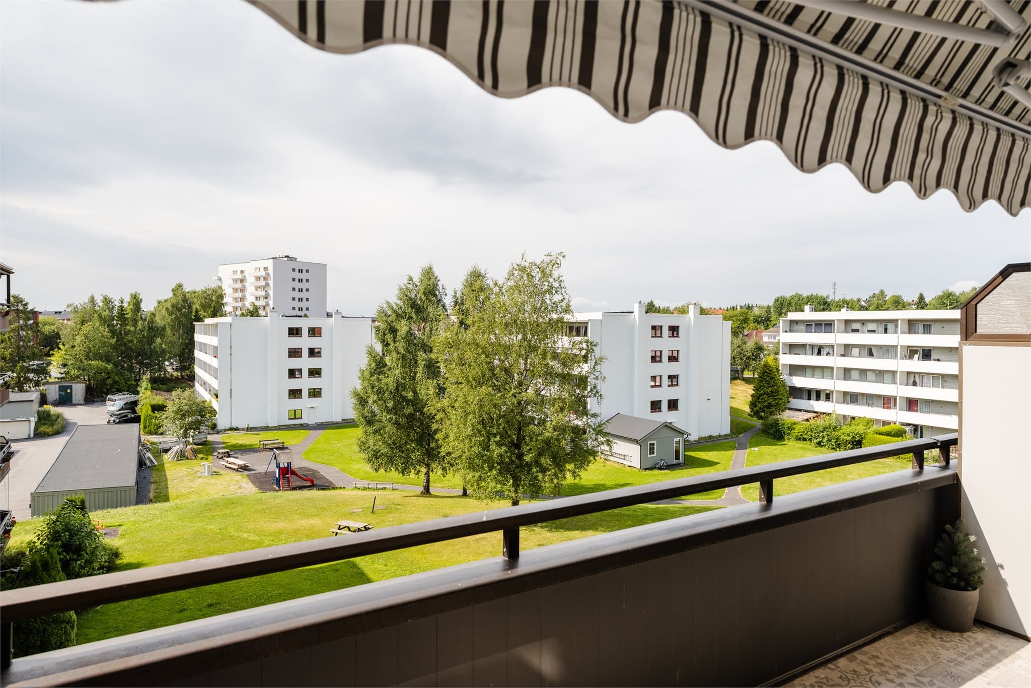 Den overbyggede løsningen gjør balkongen lun og anvendelig, med utsyn mot grøntarealer og omkringliggende bebyggelse.