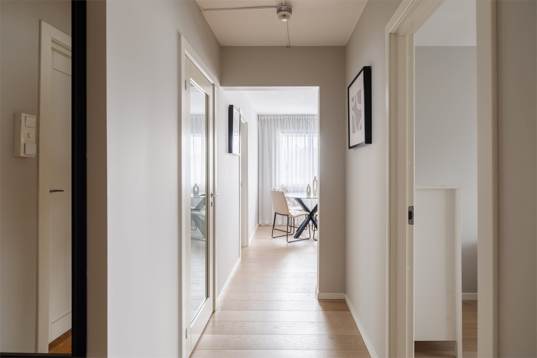 Lys entré med glassdør som slipper dagslyset videre inn i leiligheten.