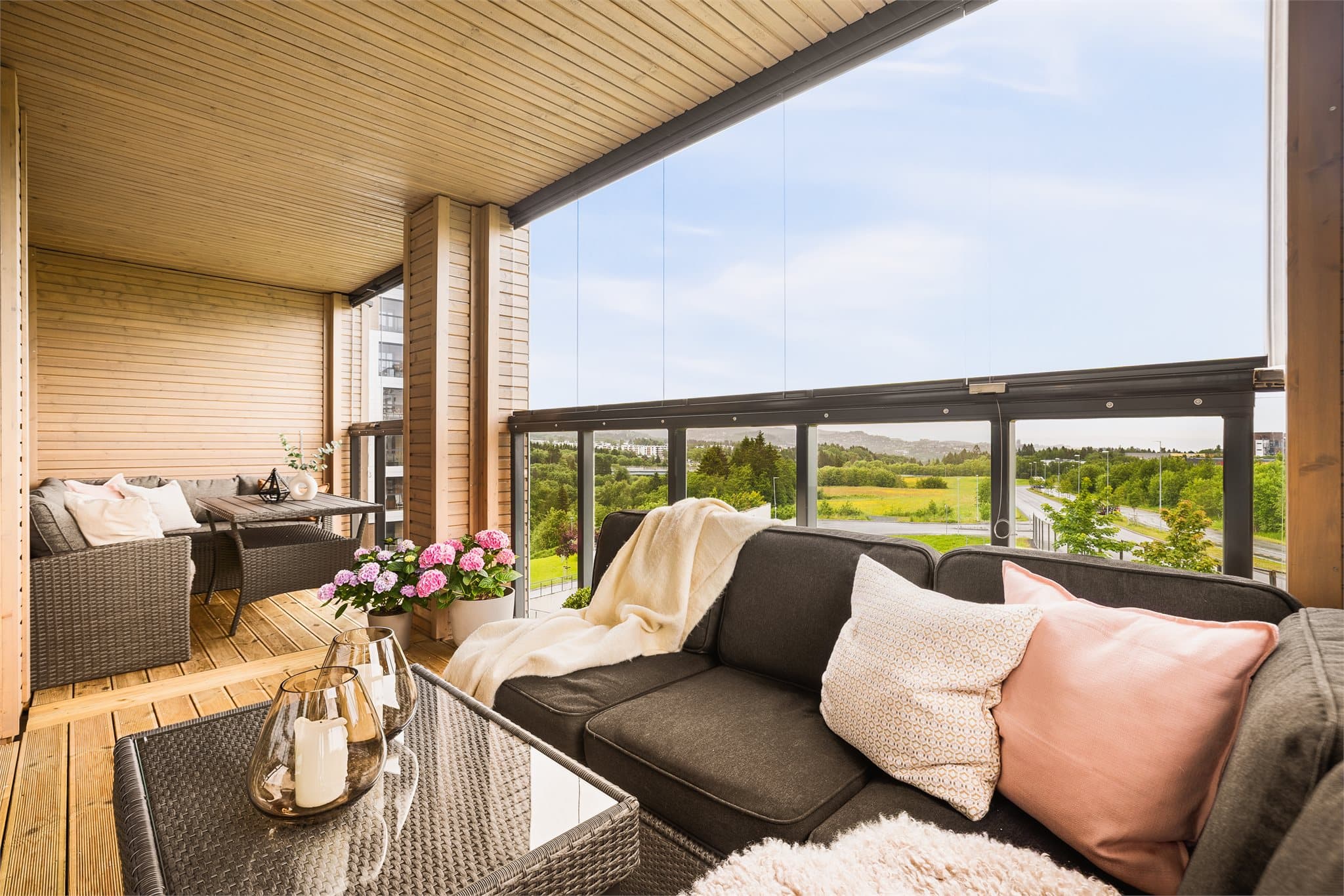 Balkongen har god plass til både spisesone og loungesone – her er det utsikt over grøntområder og åpen himmel.