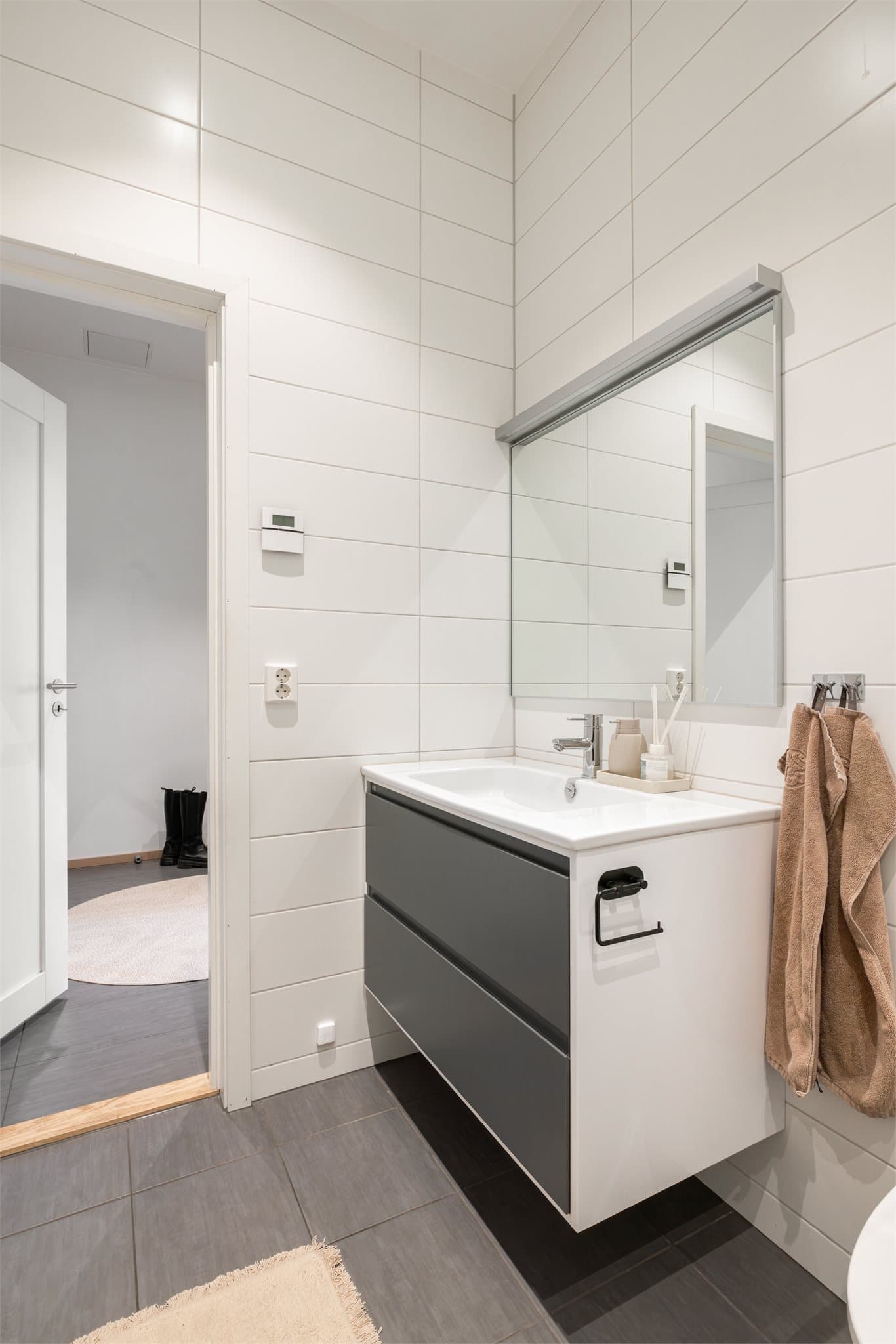Badet inneholder bl.a. vegghengt toalett, moderne servant med innredning, speil med lys, dusjhjørne med glassdører og opplegg for vaskemaskin.