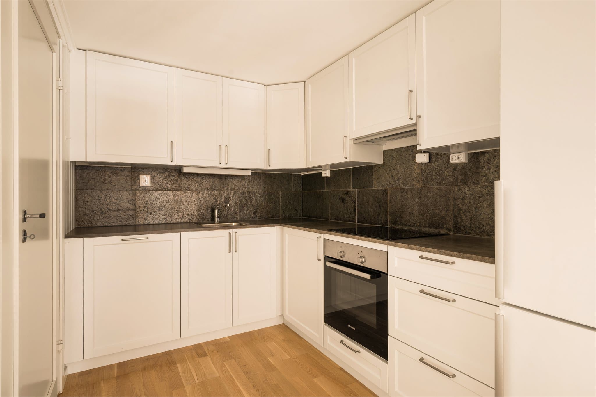 Kjøkkeninnredningen har lyse, profilerte fronter og laminat benkeplate med nedfelt kum.