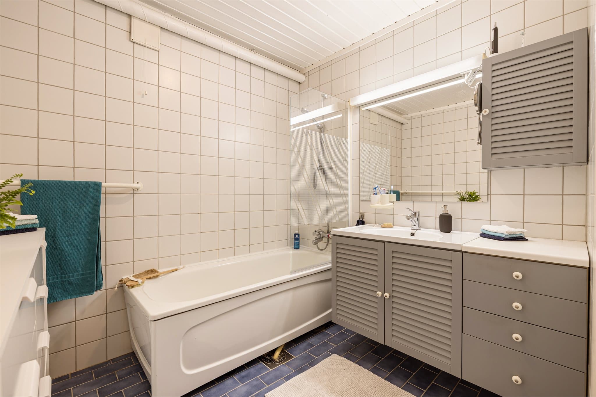 Romslig bad på ca. 5 kvm med badekar og servantinnredning.