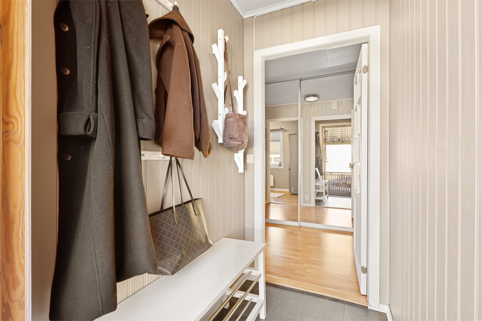 Innbydende entré med videre adkomst til gang med innebygd garderobe med speildører.