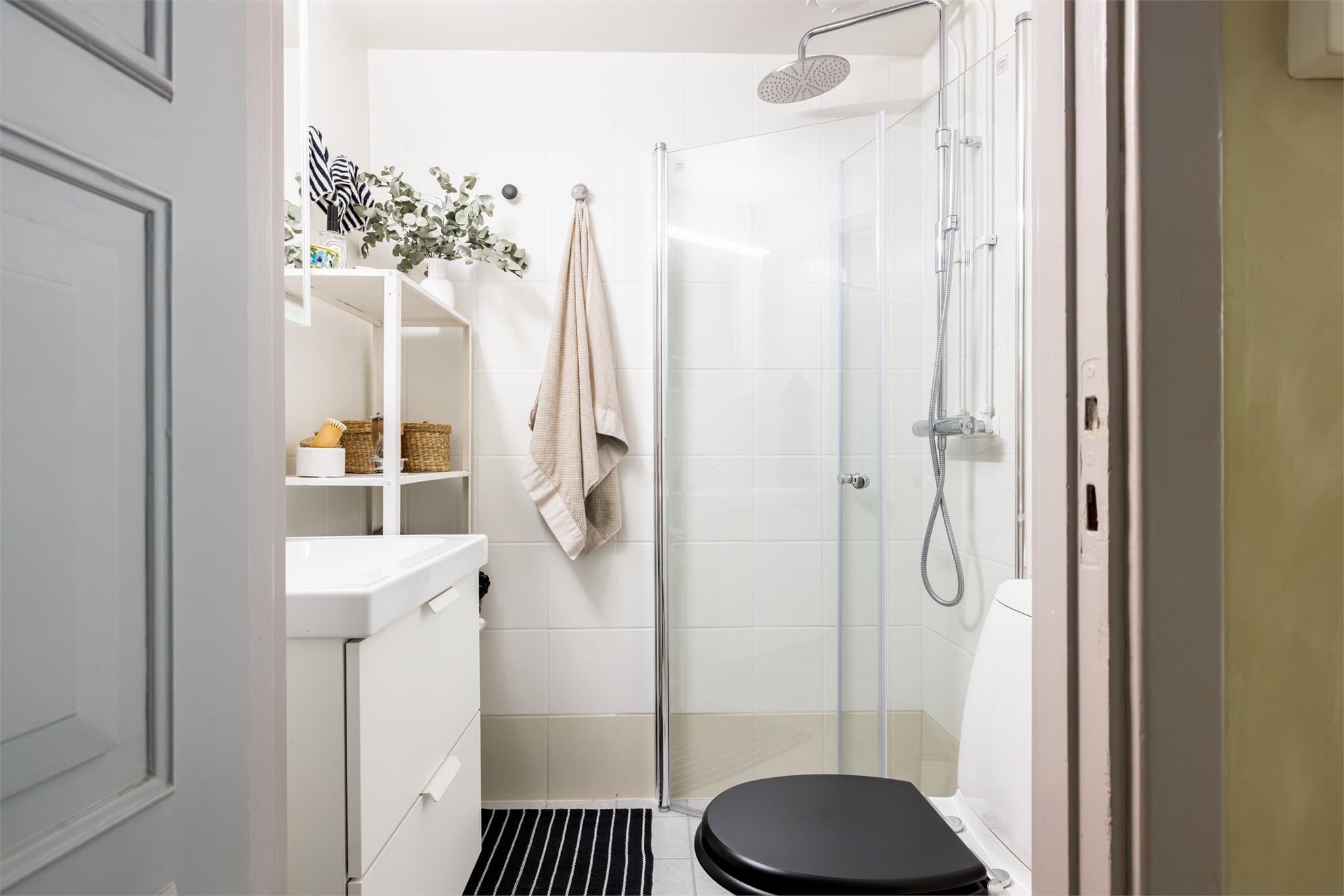 Flislagt baderom fra 2004 med moderne løsninger. Servantskap med glatte, folierte fronter og heldekkende servant, speilskap med lysarmatur over.