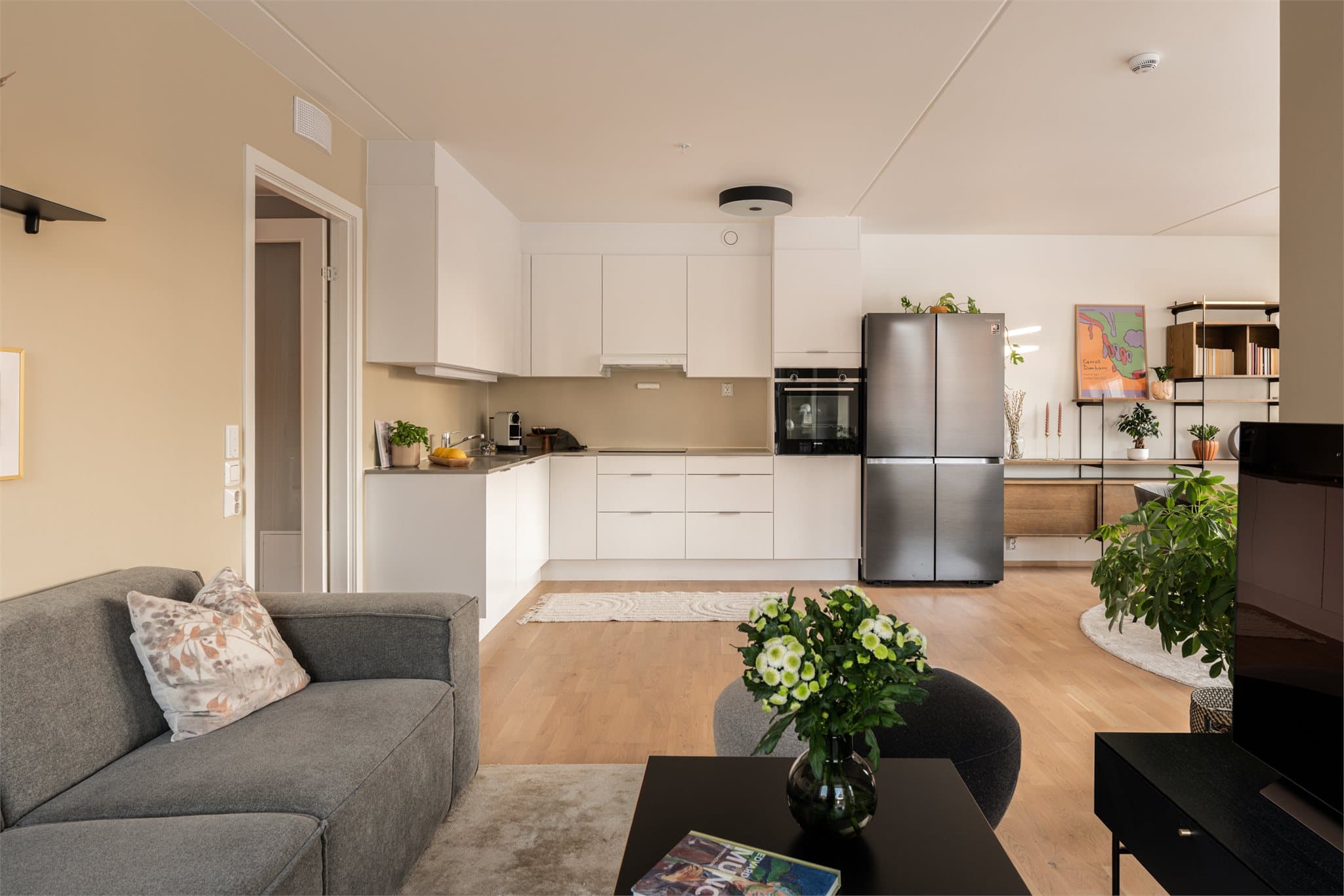 Stort, flott oppholdsrom med et stilrent kjøkken i åpen løsning.