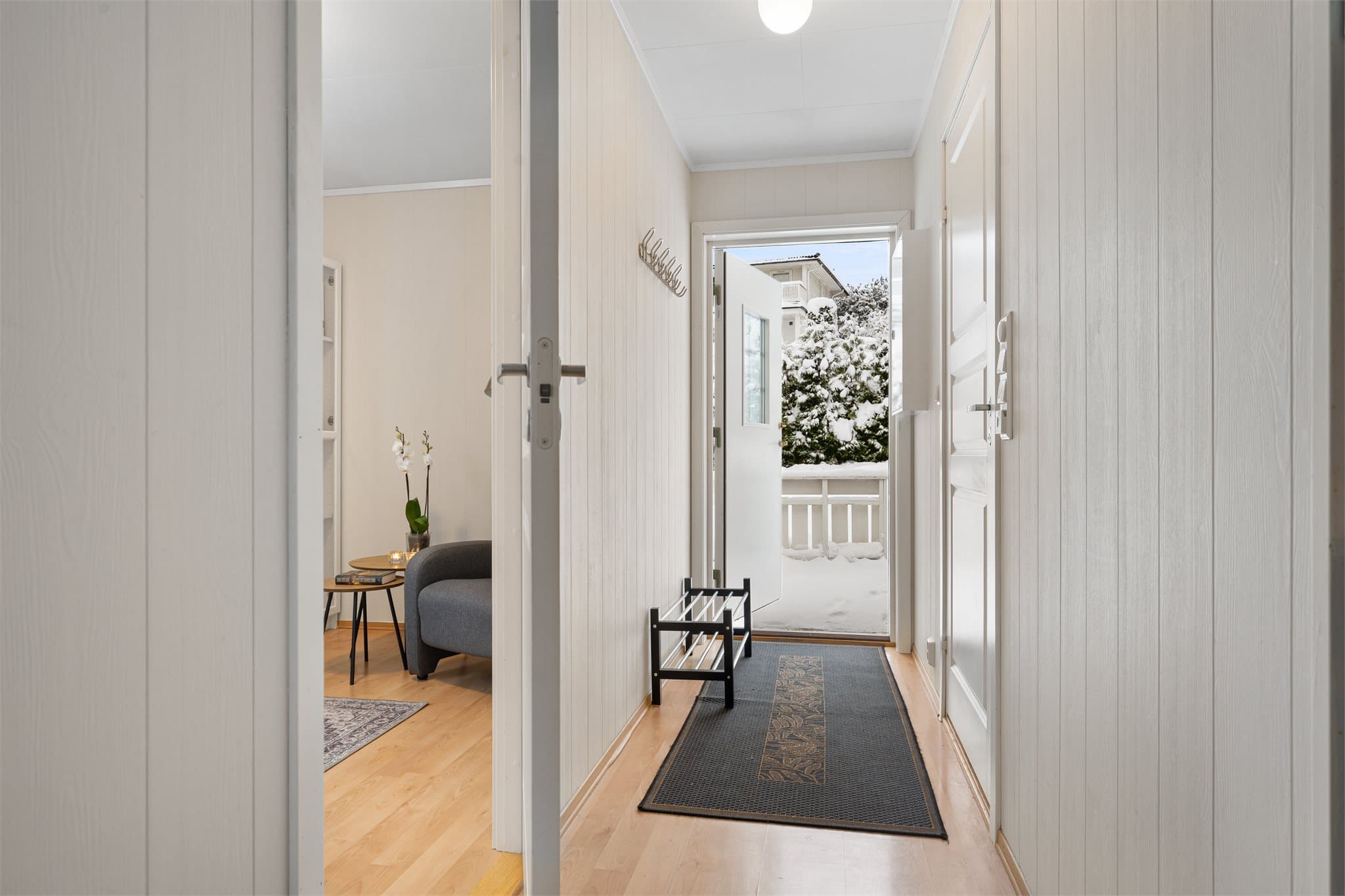 Velkommen inn! Lysmalt entré med laminat på gulv. Det er montert knaggrekke.