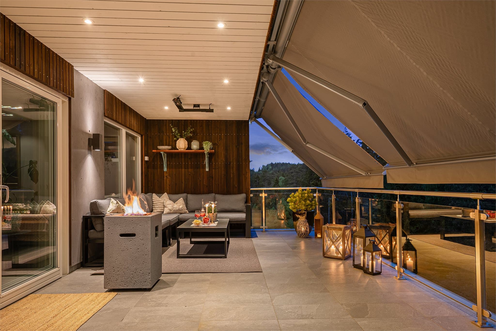 En terrasse som virkelig innbyr til bruk fra tidlig vår til sen høst. Den elektriske markisen kan kjøres helt ut og skaper en skjermet og lun uteplass, kombinert med elegante fliser og stemningsfulle downlights.