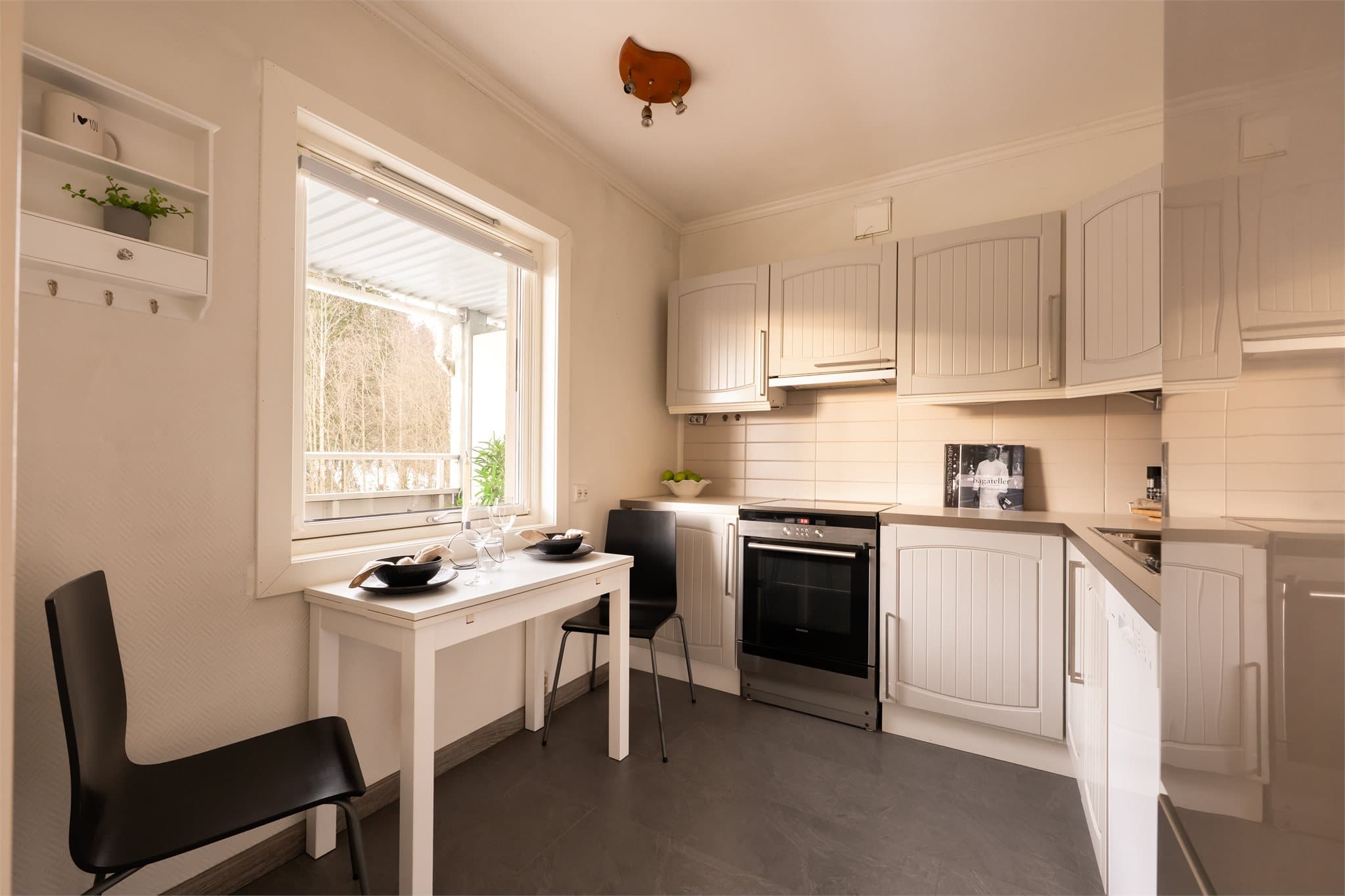 Separat kjøkken med innredning med profilerte og fabrikklakkerte fronter. Videre er det benkeplate i laminat med nedfelt kum i rustfritt stål samt fliser over benkeplate. Det er belysning via lysstoffrør under overskap.