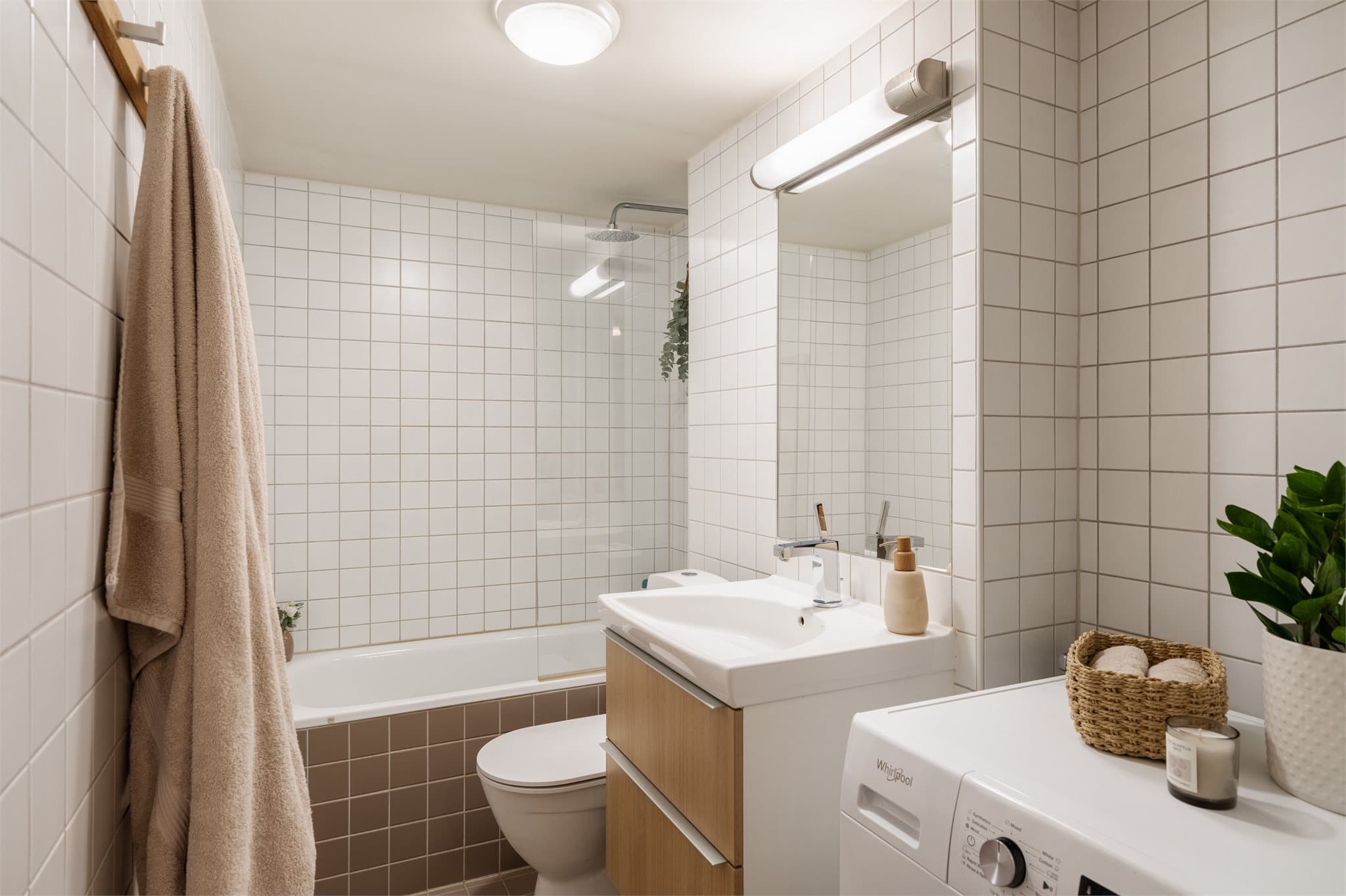 Flislagt bad med elektriske varmekabler i gulvet, badekar og opplegg for vaskemaskin.