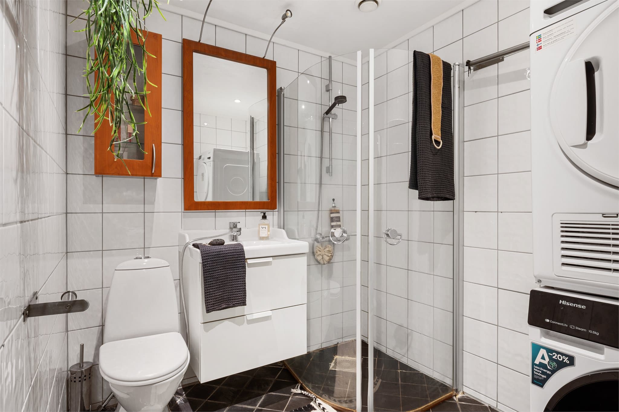 - Badet er innredet med heldekkende servant, speil med belysning, toalett, veggskap, dusj med foldedører og opplegg for vaskemaskin -