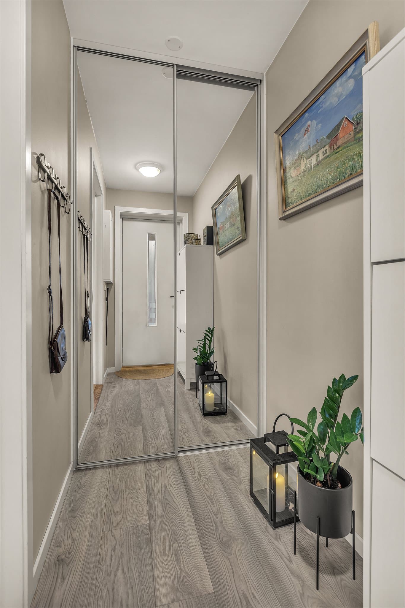 Gangen er innredet med en romslig skyvedørsgarderobe med speilfronter.