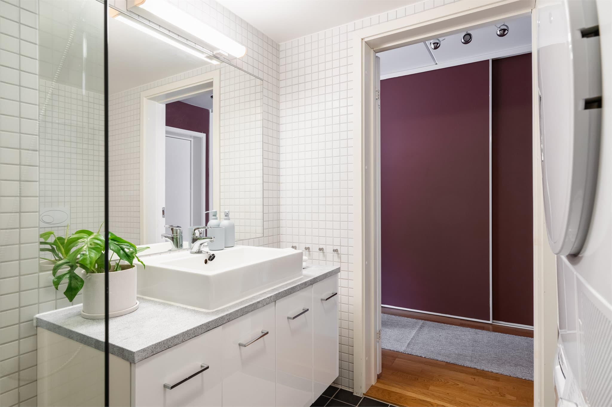 Baderomsinnredningen består av servantmøbel, vegghengt toalett og et innfelt speil med belysning over.