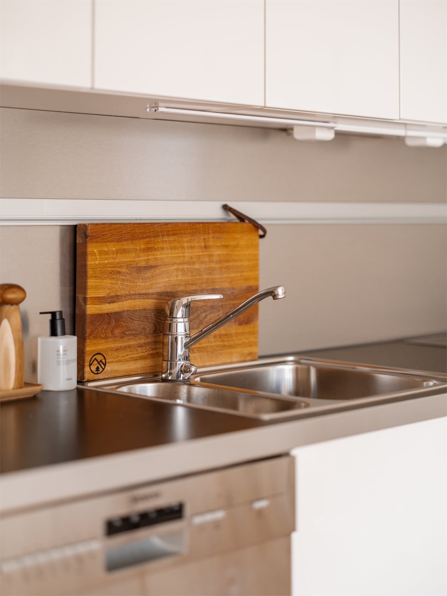 Praktisk laminatbenkeplate med nedfelt vaskekum og en plate i børstet stål som beskytter veggen.