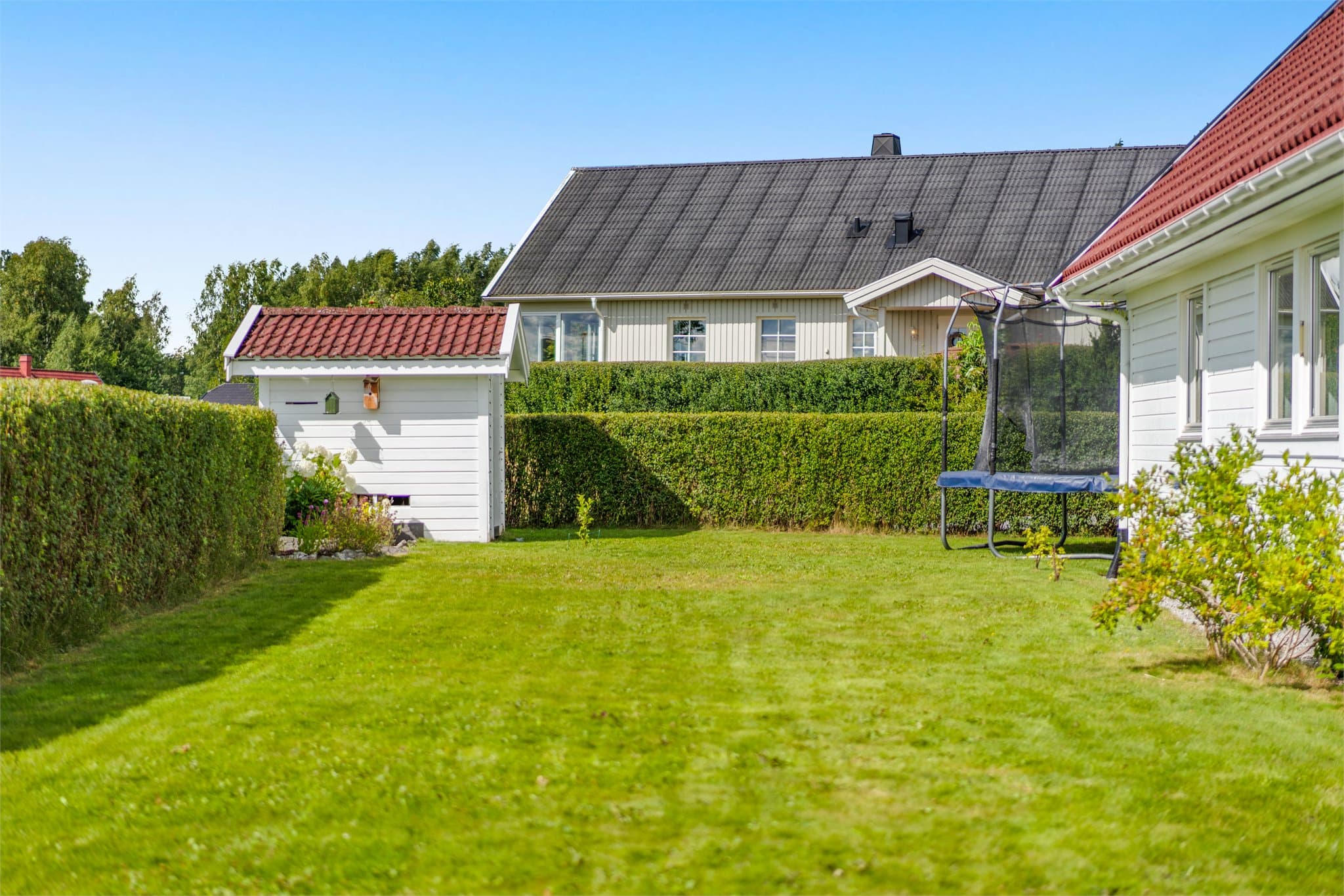 Hage med uthus/ vedskjul for praktisk oppbevaring av ved og hageutstyr