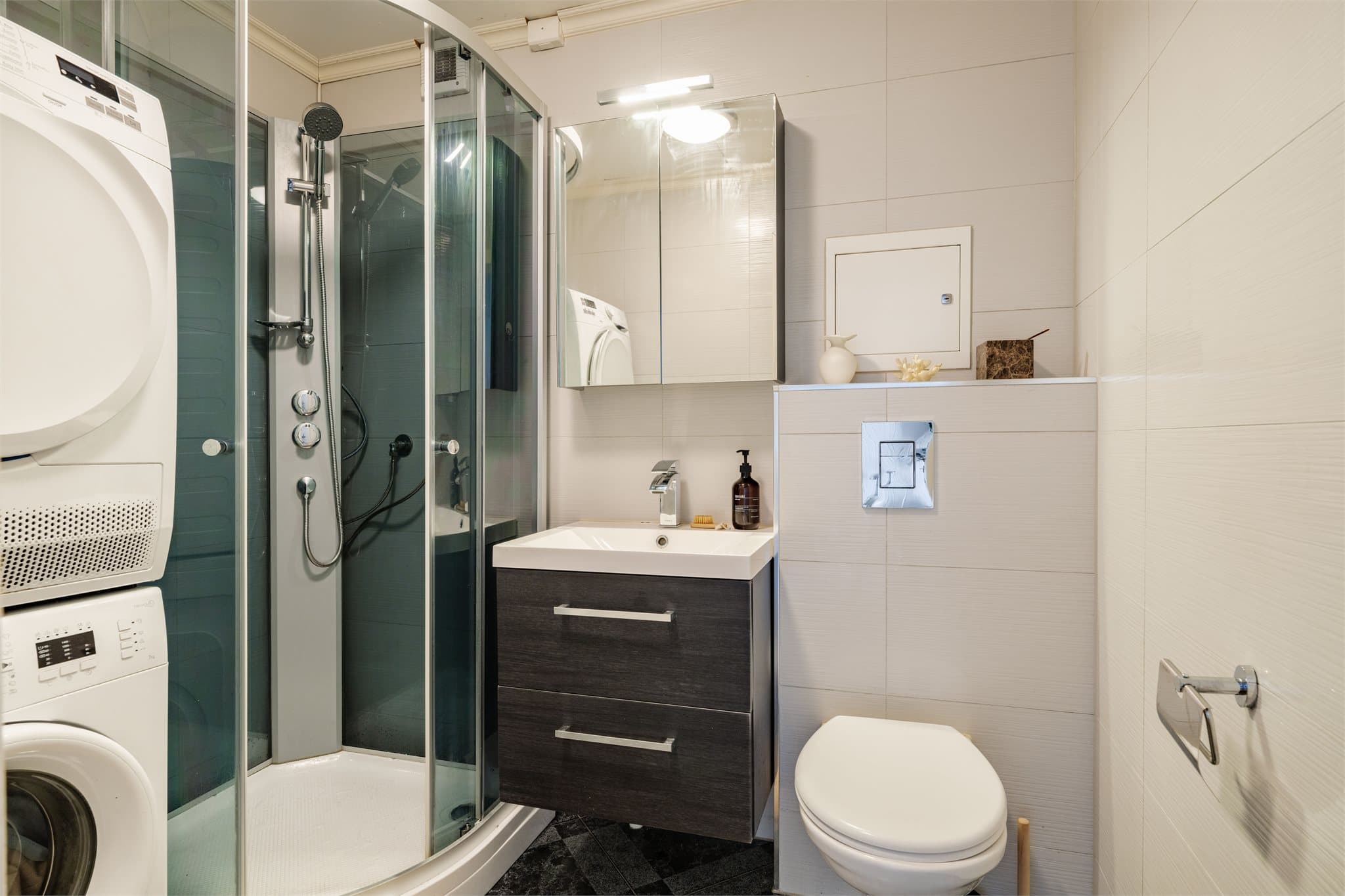 Badet i første etasje har flislagt gulv med varmekabler, dusjkabinett, vegghengt toalett og opplegg for vaskemaskin.
