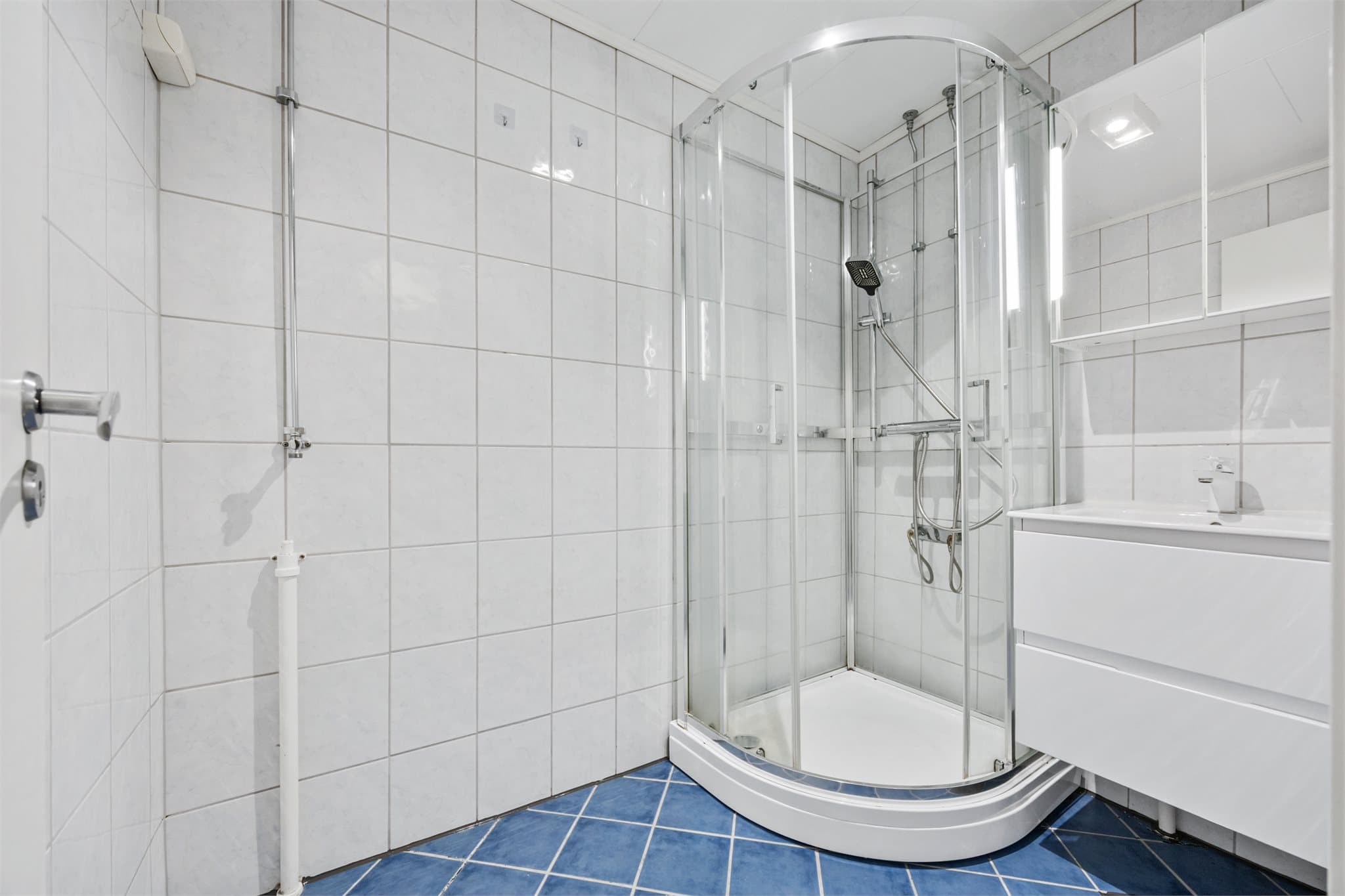 Badet inneholder vegghengt servant og dusj kabinett