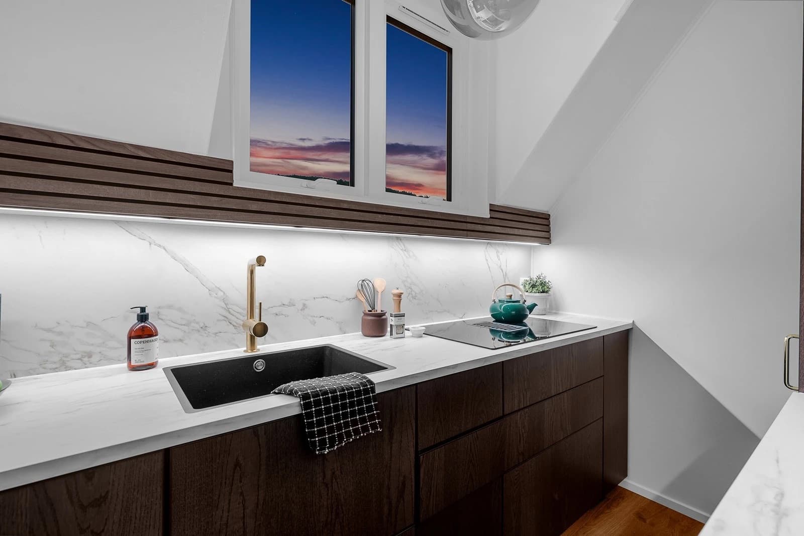 Lekkert kjøkken fra 2024 med integrerte hvitevarer, herav platetopp med integrert avtrekksvifte, oppvaskmaskin, stekeovn og kombi kjøl/frys.