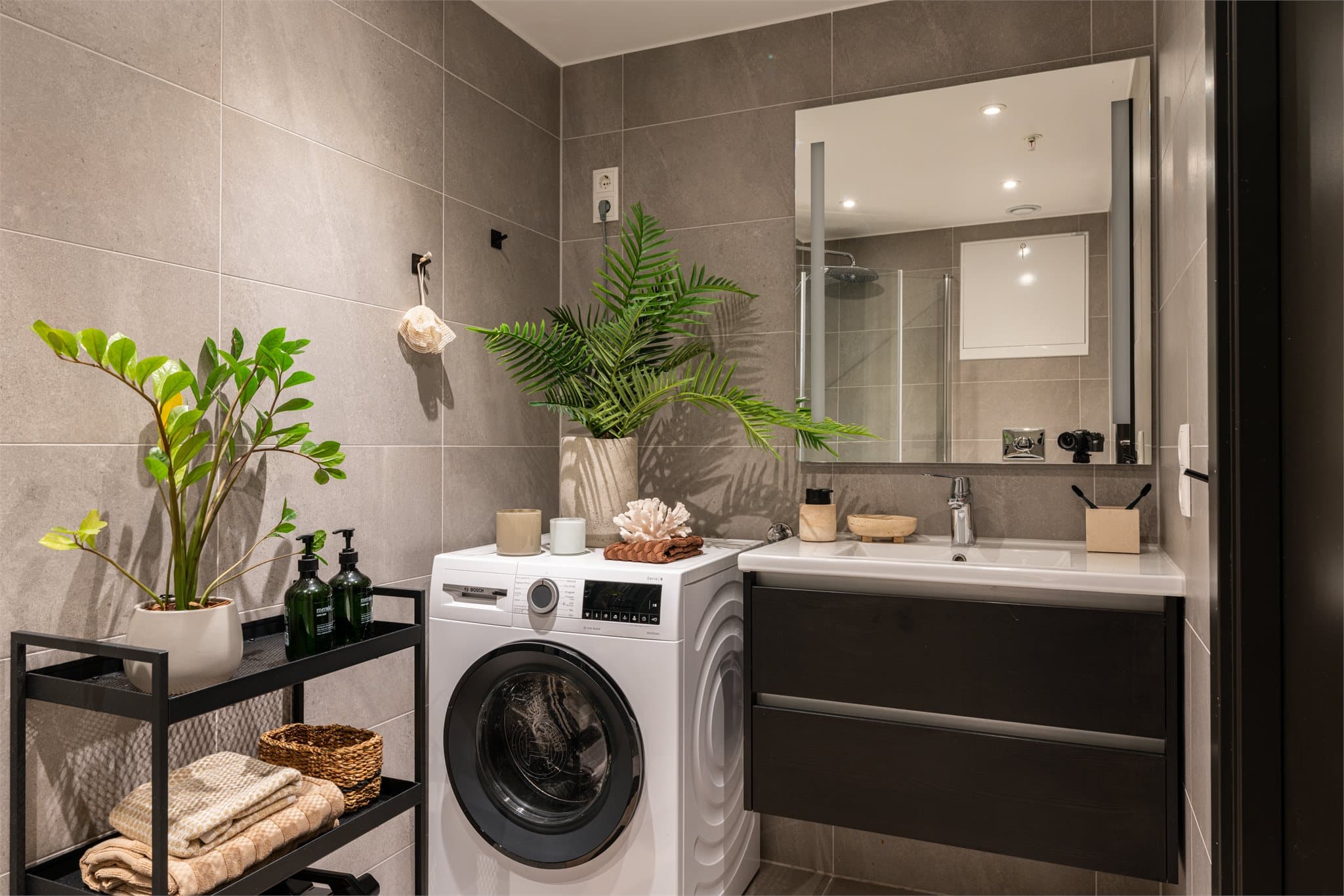 Badet har et moderne og gjennomført uttrykk med store fliser på vegger og gulv.