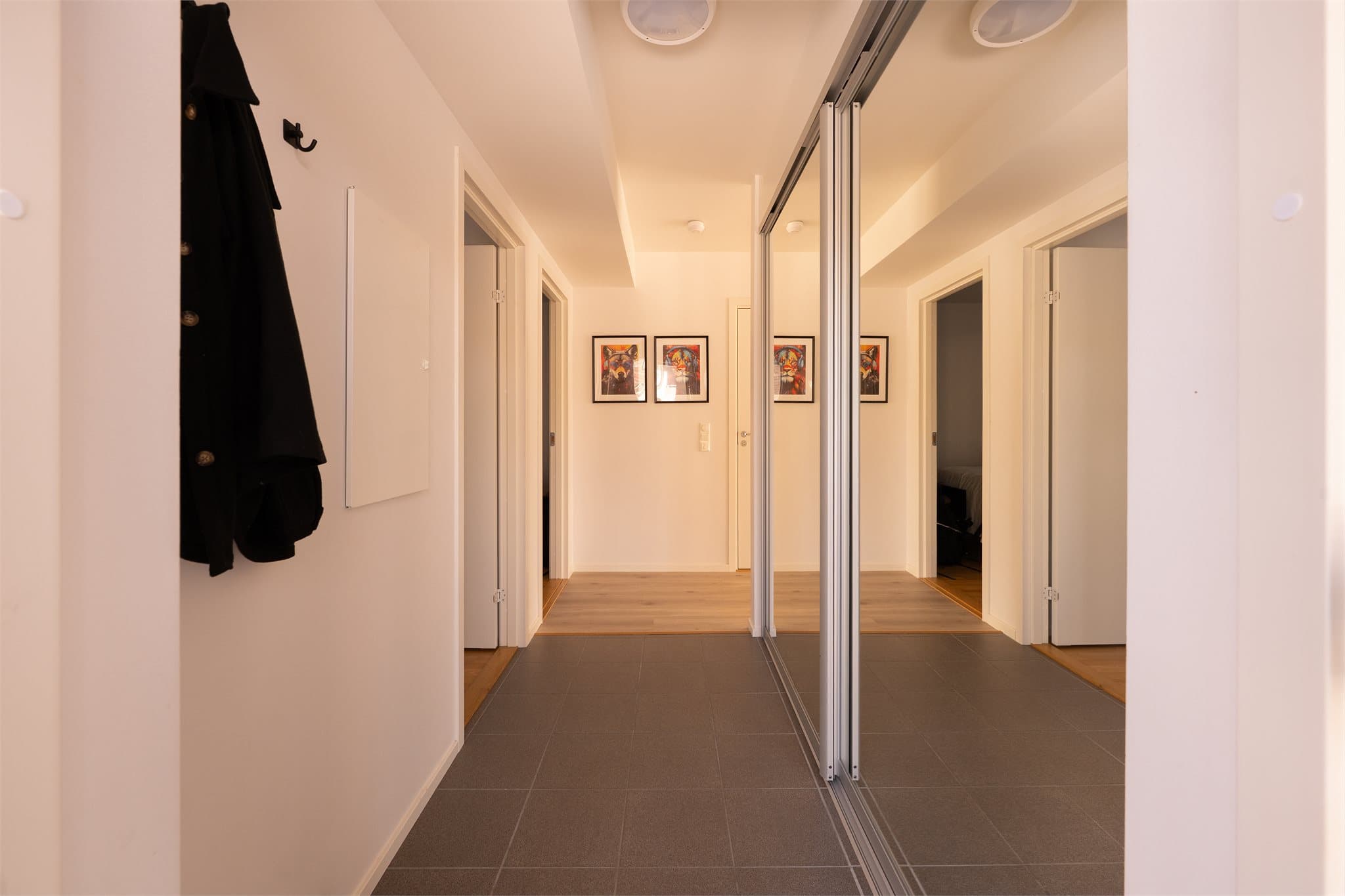 Entreen har fliser på gulv og det er skyvedørsgarderobe med speilfronter.