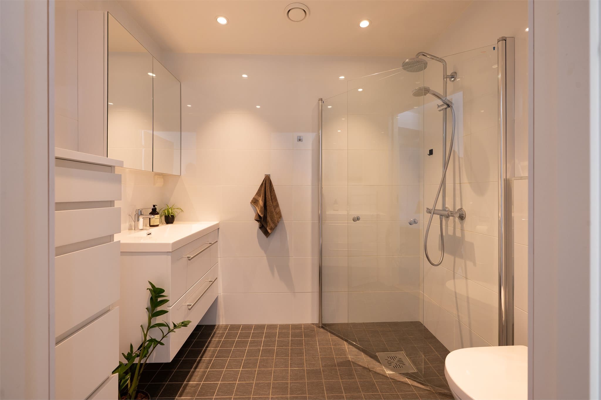 Tidløst baderom med gulvvarme og downlights i himling.