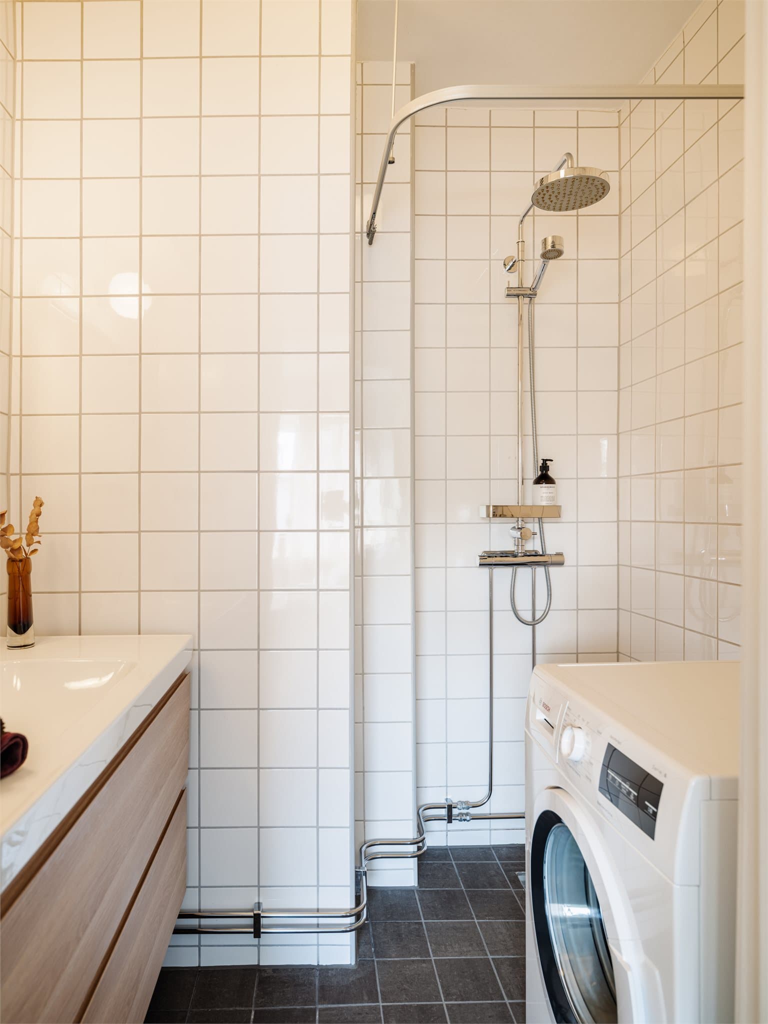 Flislagt bad med dusjnisje og opplegg for vaskemaskin.