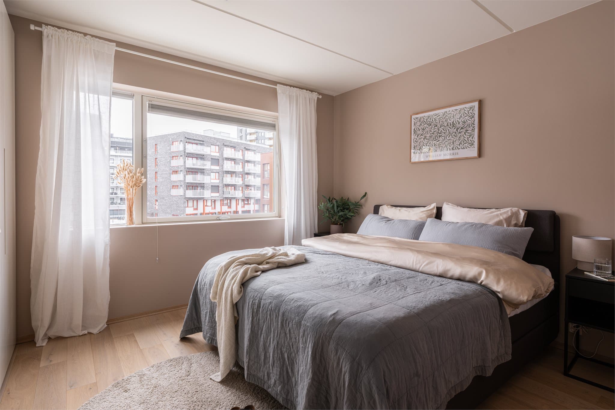 Luftig og delikat hovedsoverom med mye naturlig lys fra store vindusflater.