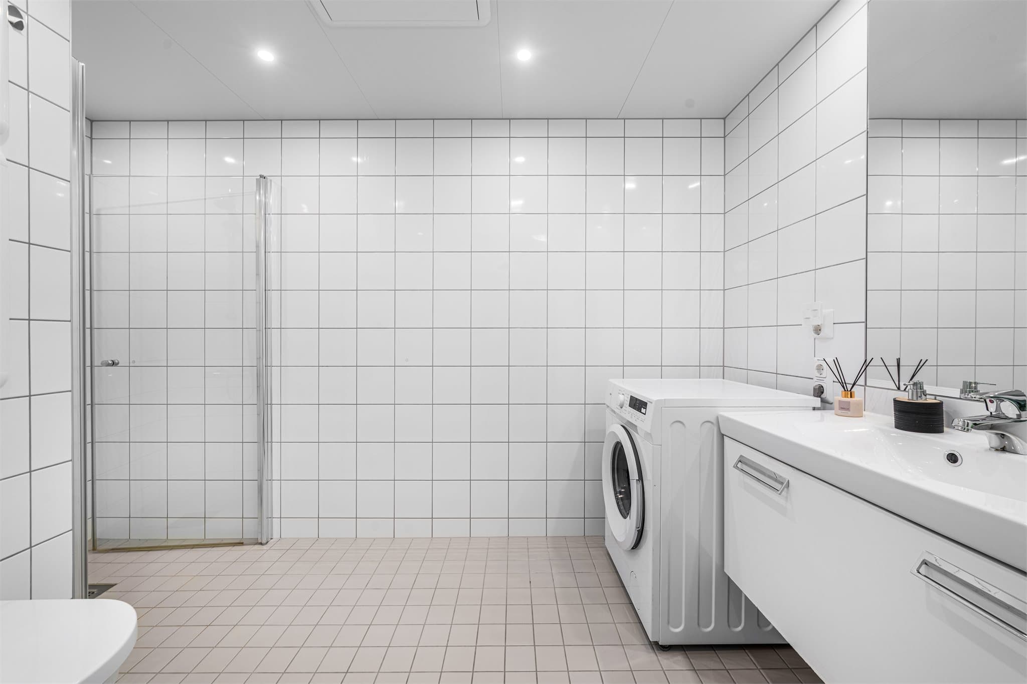 Badet er innredet med dusjnisje, servant på skuffeseksjon og vegghengt toalett. Opplegg for vaskemaskin.