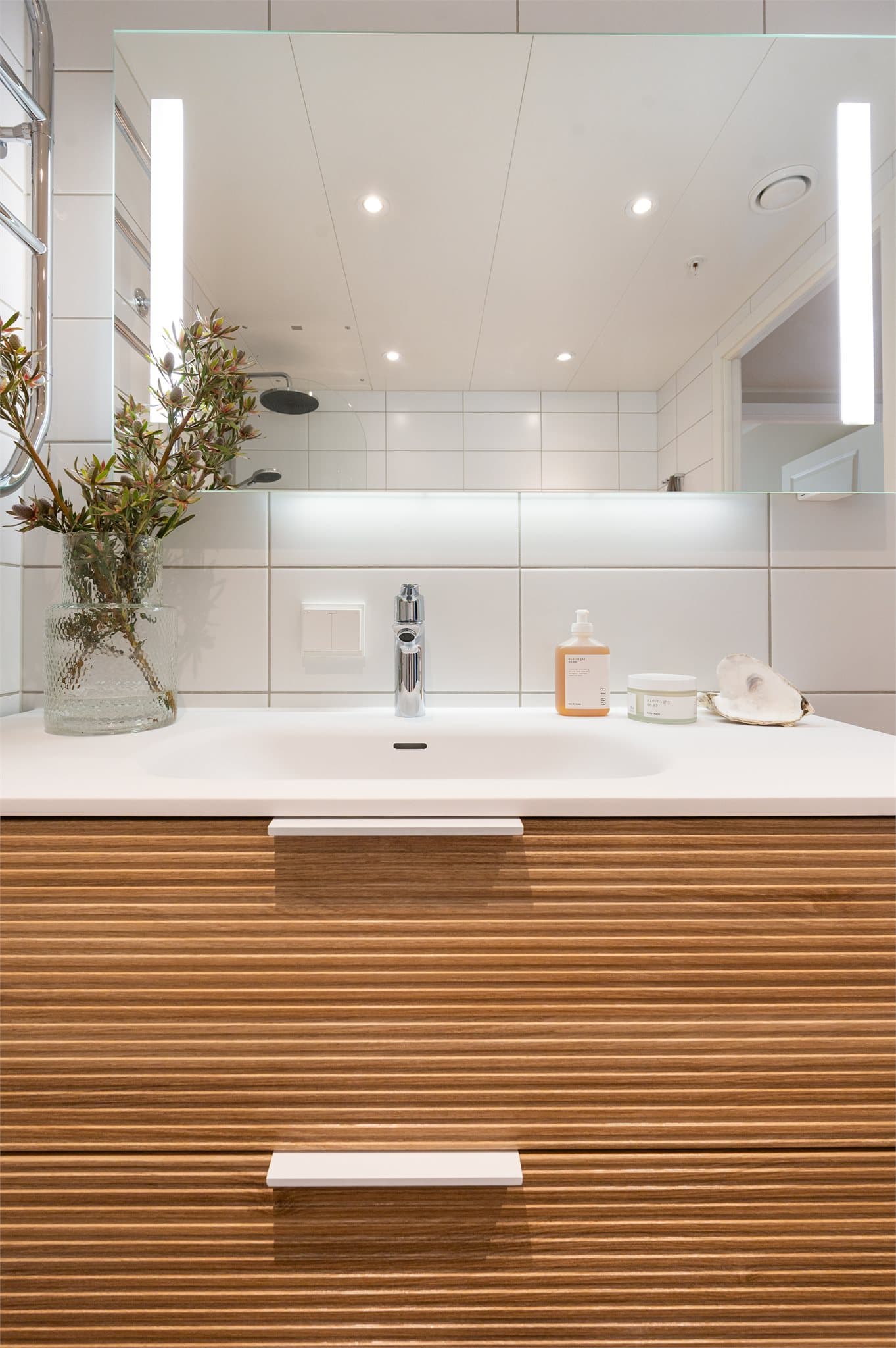 Servantinnredning med skuffer under og speil med lys.