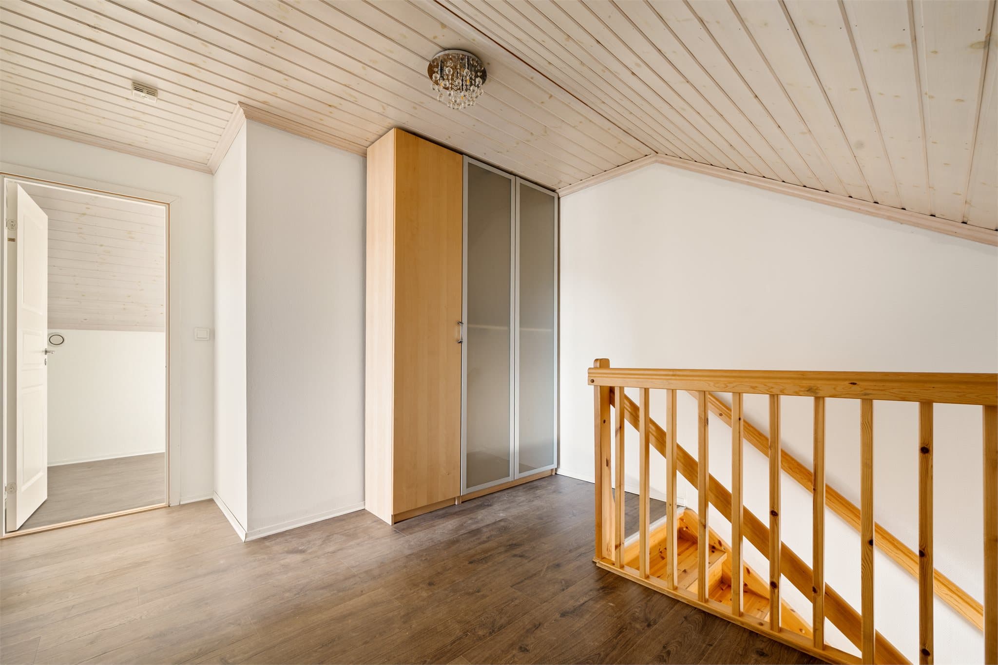 Trappegangen i loftsetasjen fremstår som både lys og funksjonell, med samme slitesterke laminatgulv som gir en helhetlig og moderne følelse gjennom boligen. Her er det god plass til oppbevaring i et stort garderobeskap i varm bjørkefarge.