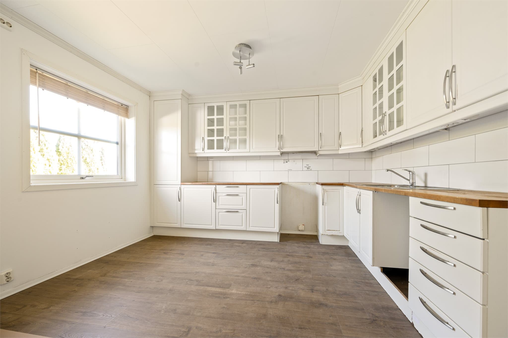 Kjøkkeninnredningen har lyse, profilerte fronter og det er avsatt plass til frittstående hvitevarer.