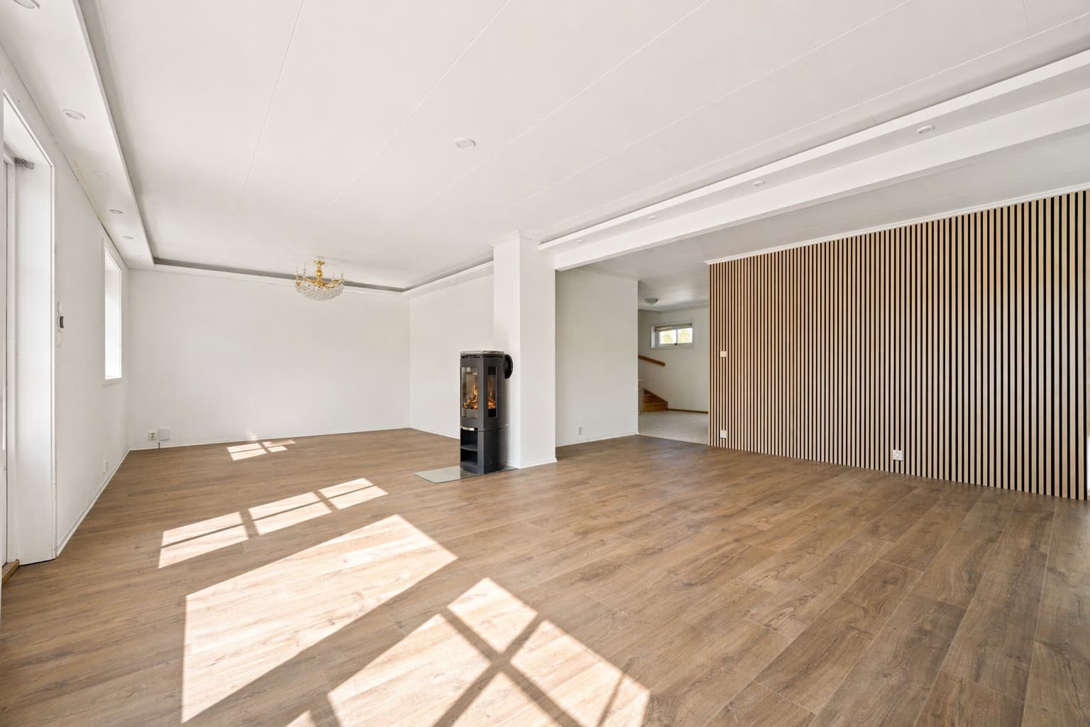 Stuen er utformet i en praktisk L-løsning som gir gode møbleringsmuligheter og en naturlig inndeling mellom sonene. Det slitesterke laminatgulvet videreføres her og skaper en helhetlig og moderne base.