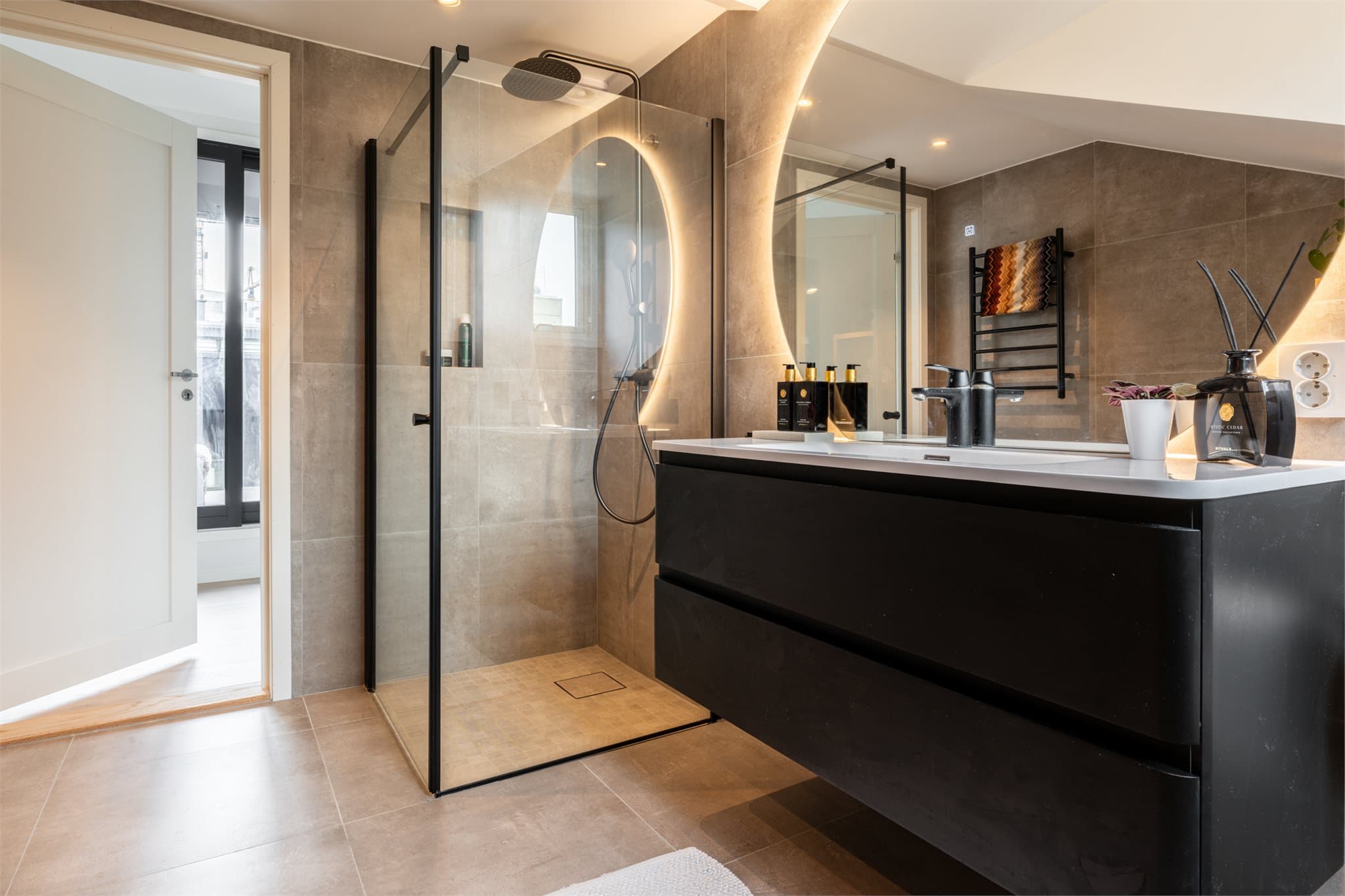 Romslig dusjnisje bak innfellbare dører i herdet glass.