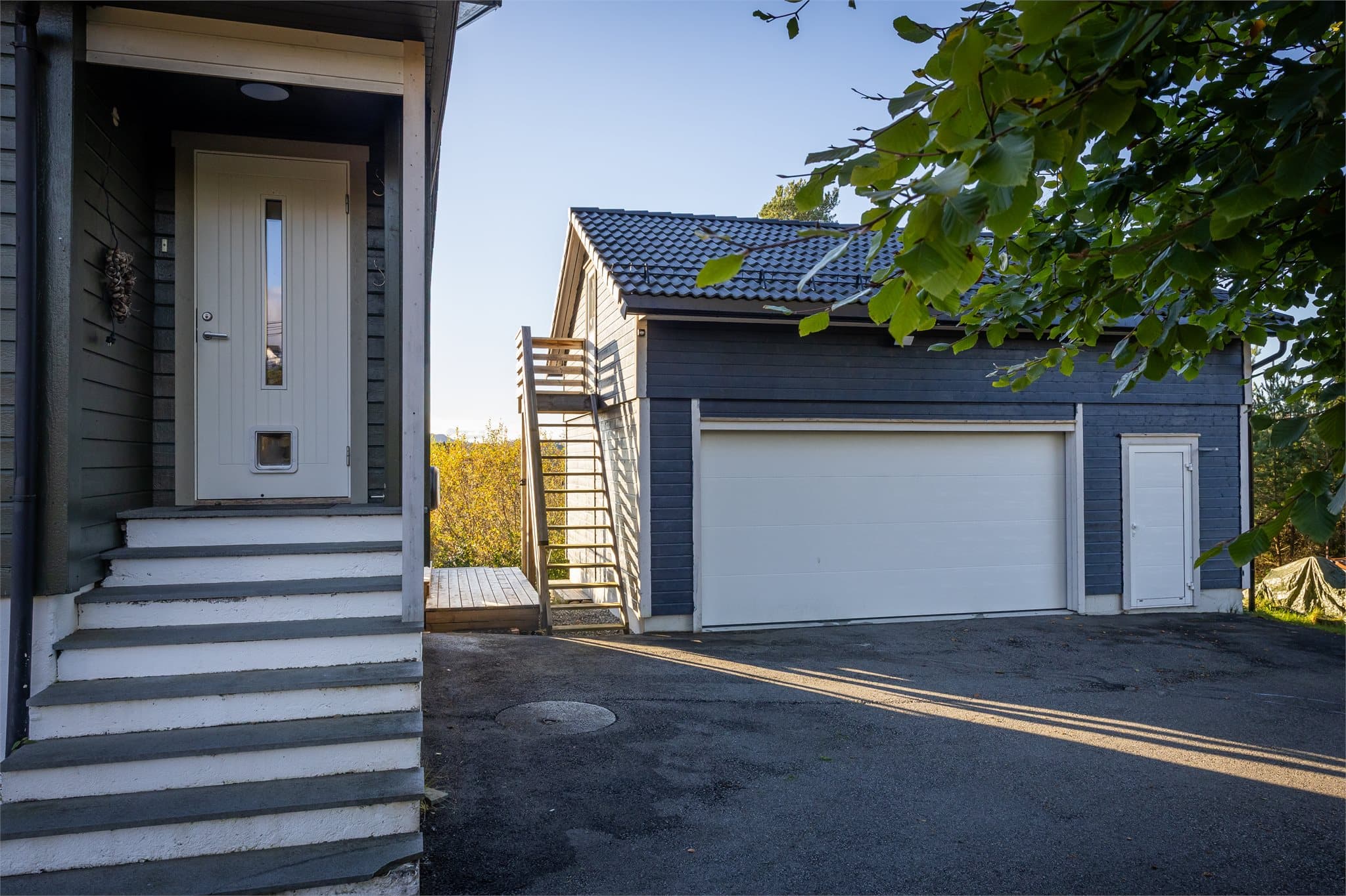 Tomten er pent opparbeidet med gressplen, hage med bed og hekk, terrasse på to nivåer og asfaltert innkjørsel og gode parkeringsmuligheter