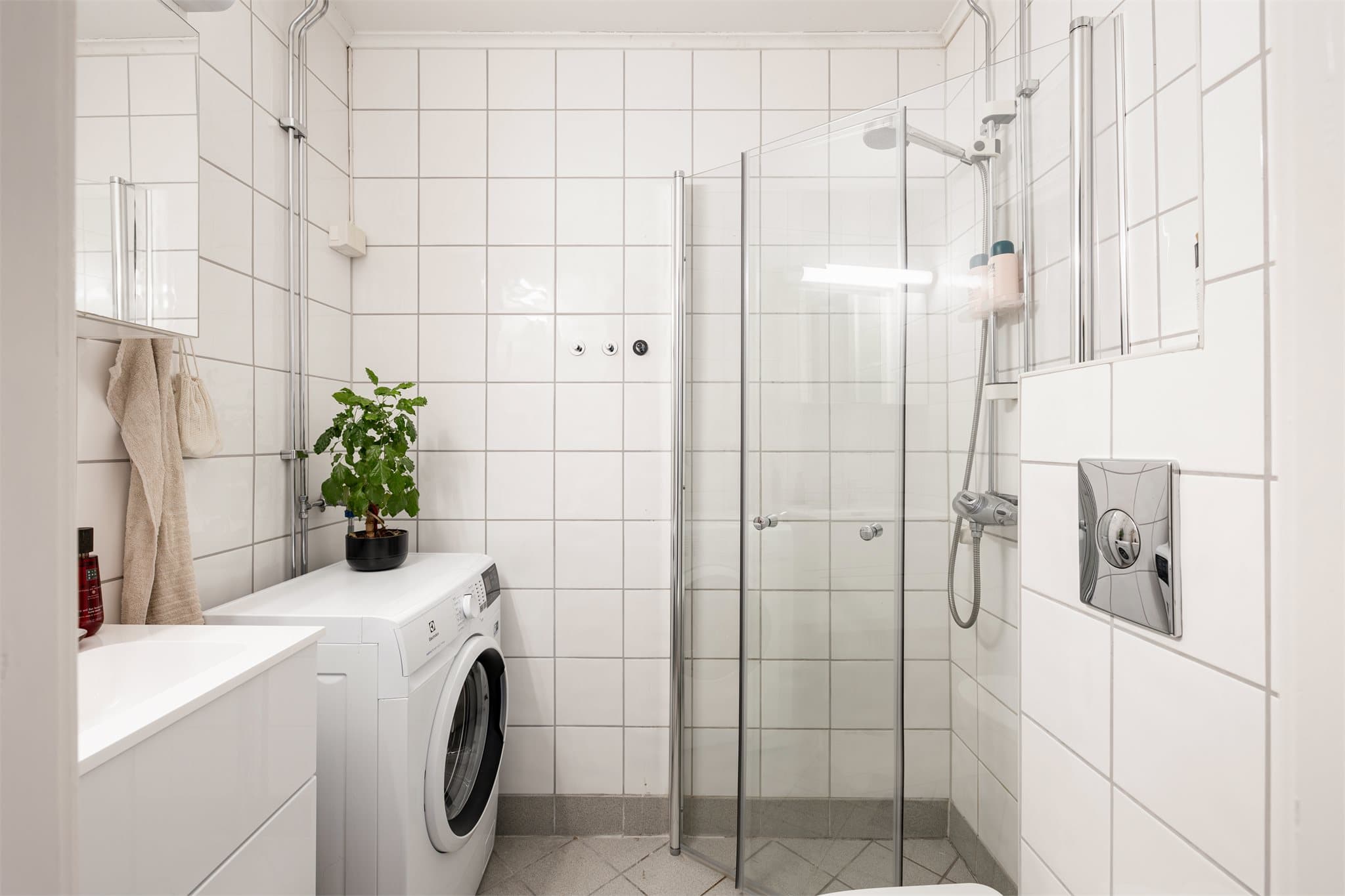 Flislagt bad med elektriske varmekabler i gulvet, dusjnisje og opplegg for vaskemaskin.