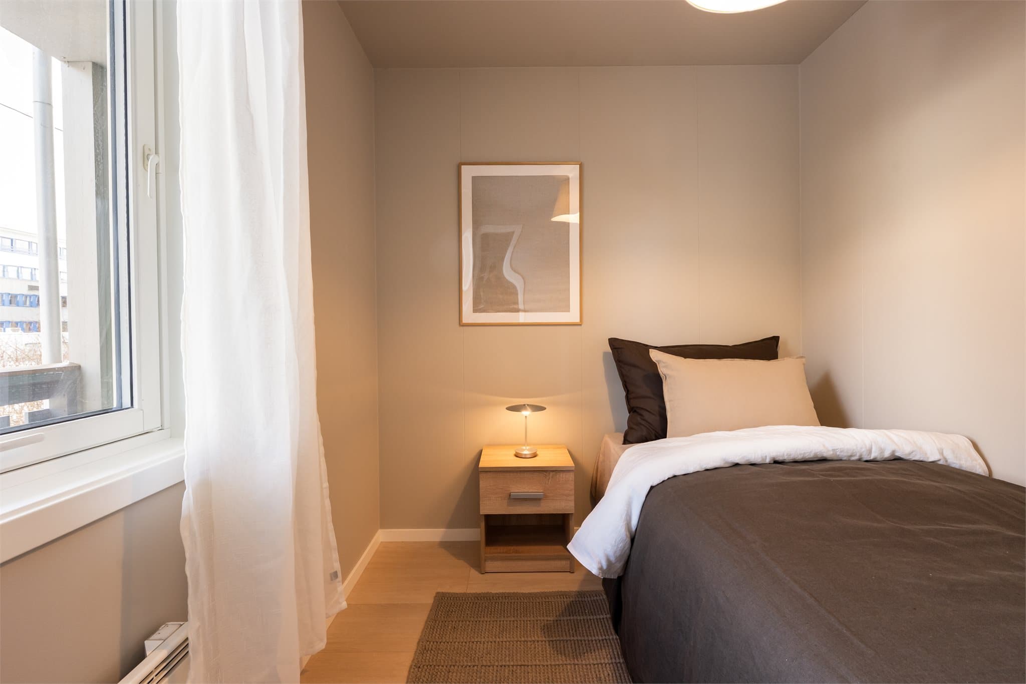 Lyst og rolig soverom med plass til seng og tilhørende møblement.