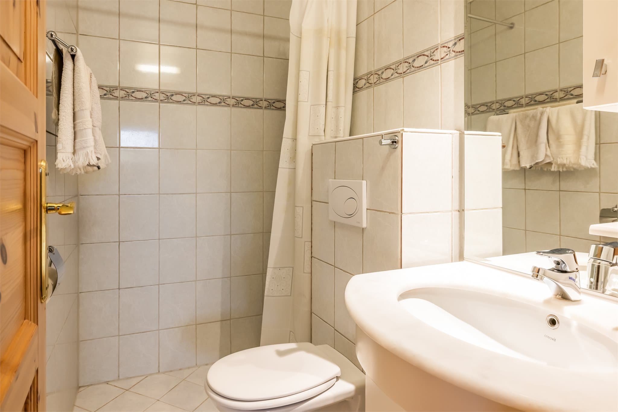 Badet måler 2,6 m² og er innredet med servantskap, speilskap med belysning, vegghengt toalett og dusj