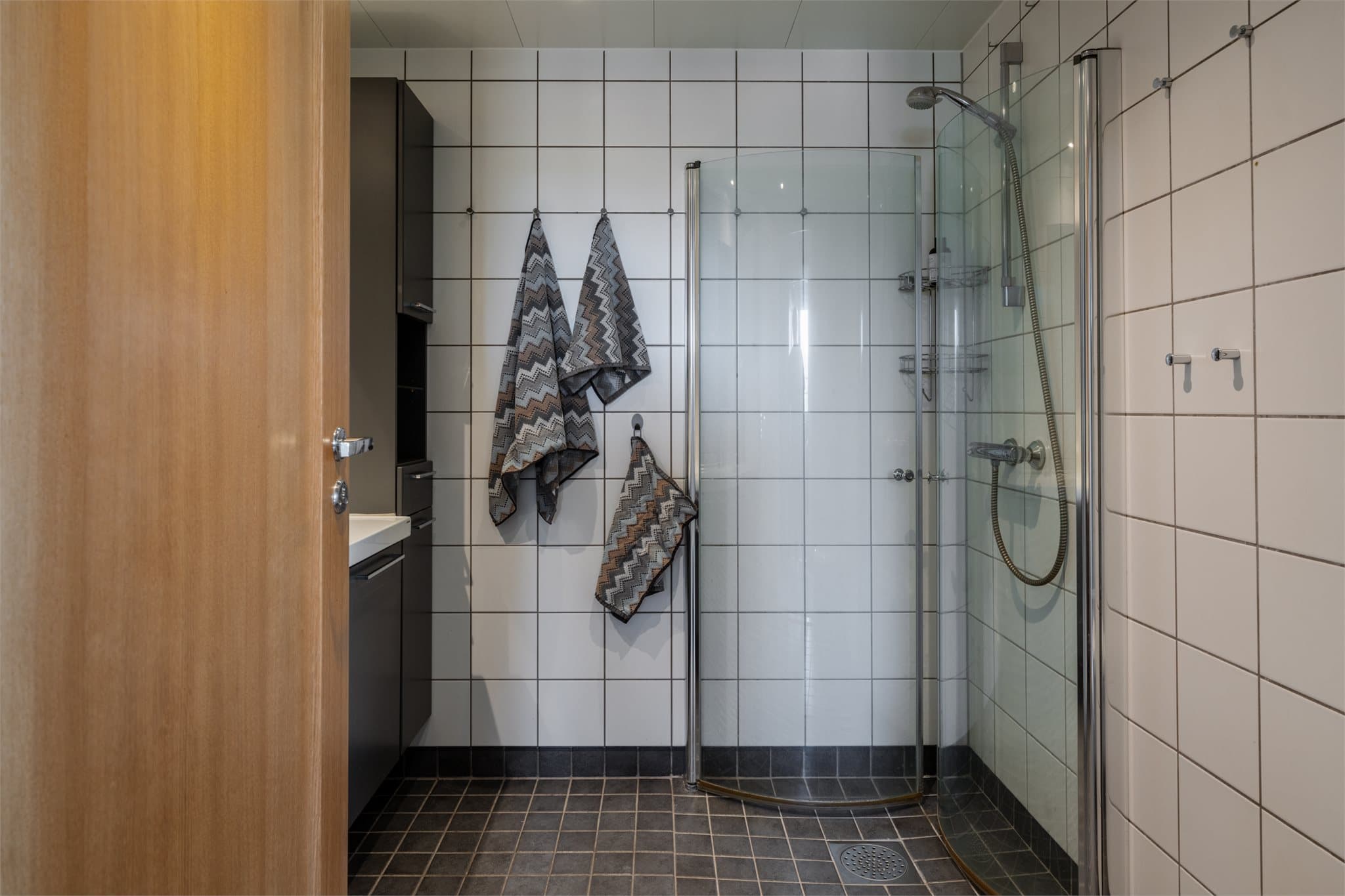 Helflist bad med dusjhjørne med innfellbare glassdører som frigjør gulvplass.