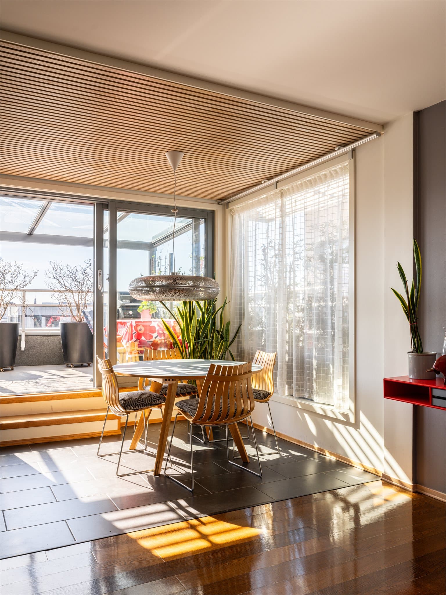 Store skyvedører i glass åpner opp mot sydsiden av terrassen og slipper dagslyset inn.