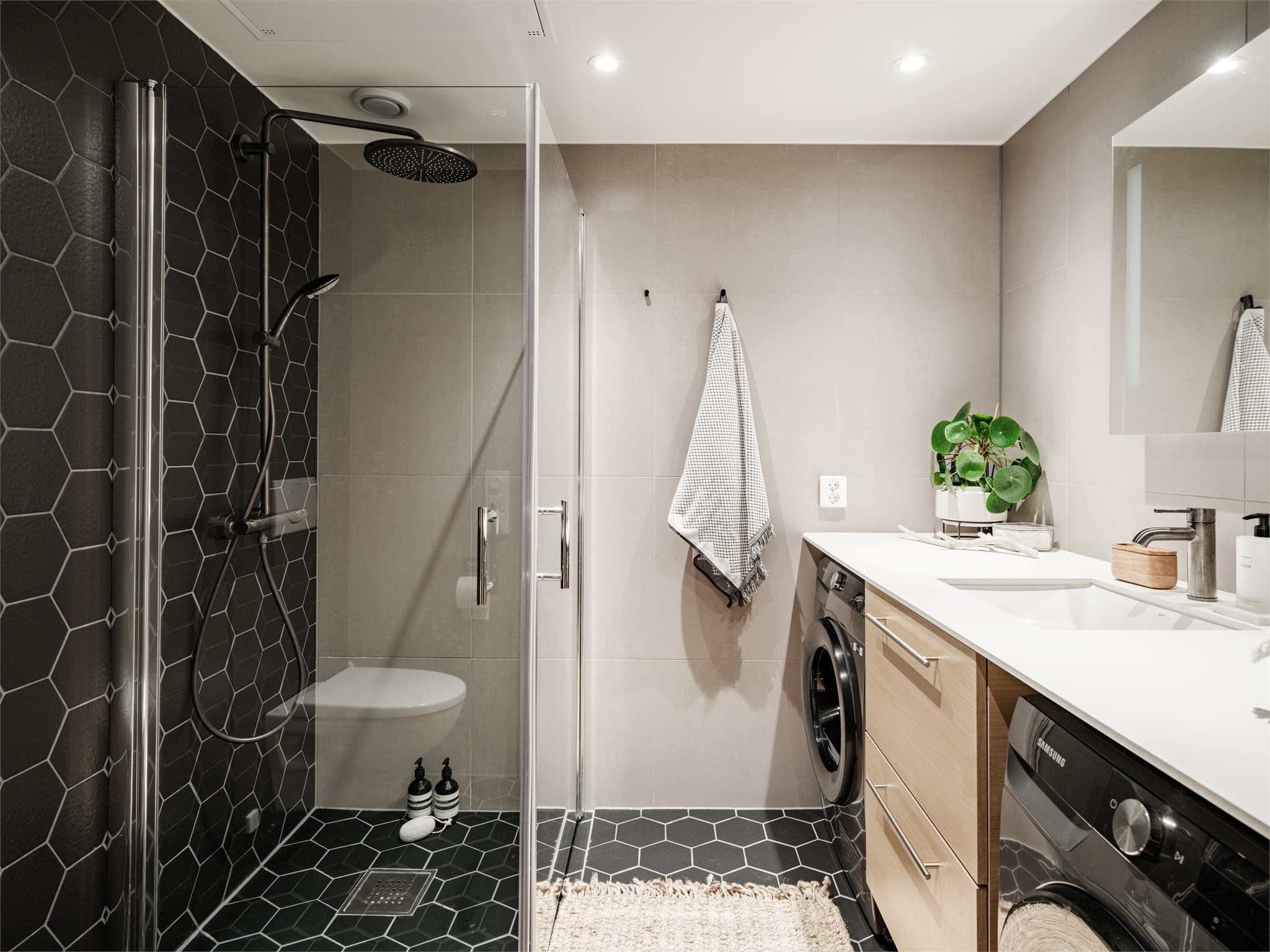 Rommet har flislagte vegger og malte plater i himlingen, med integrerte downlights som gir et behagelig og godt lys.