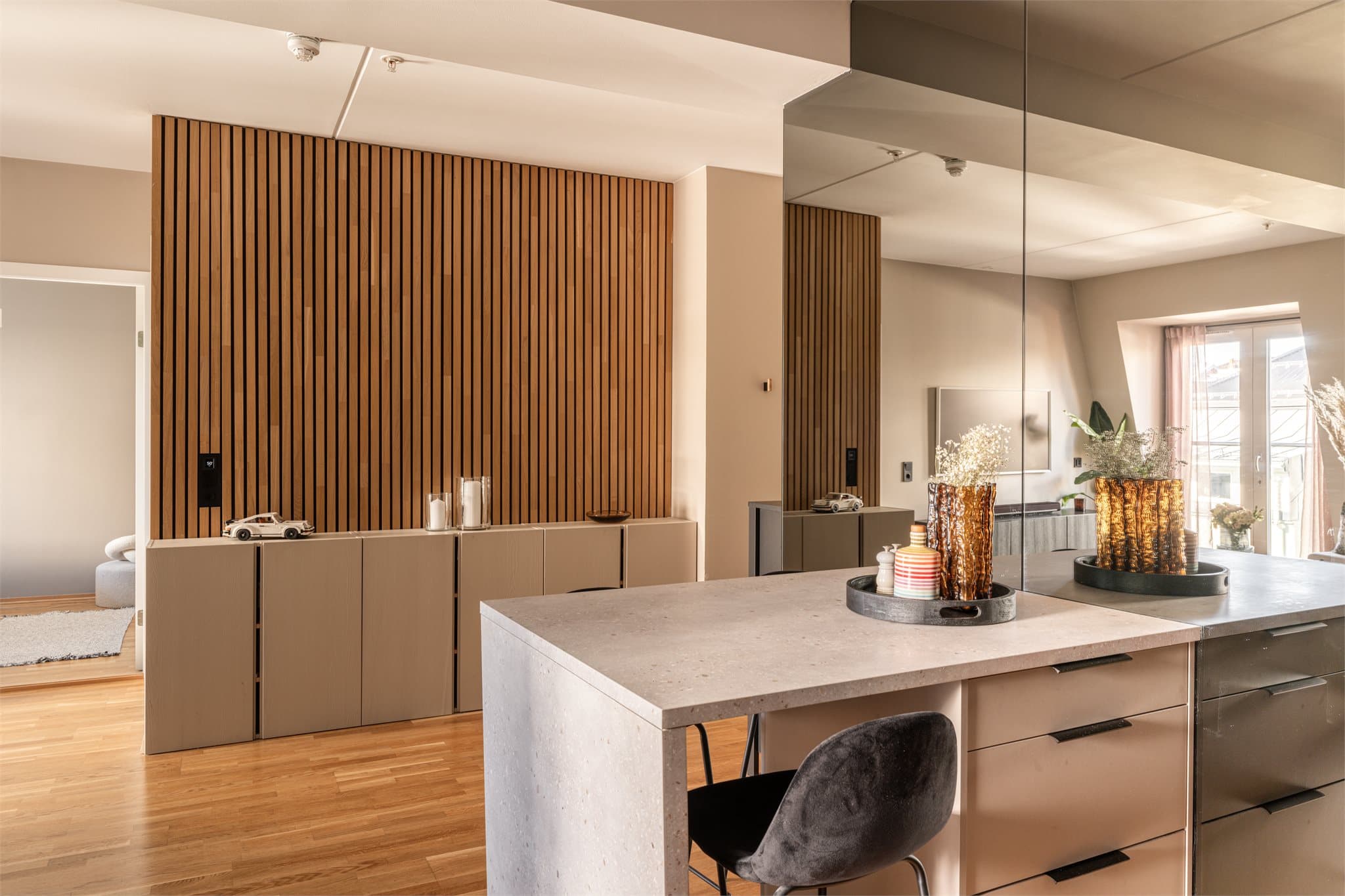 Speilveggen ved kjøkkenøya gir en forstørrende effekt og reflekterer lyset.