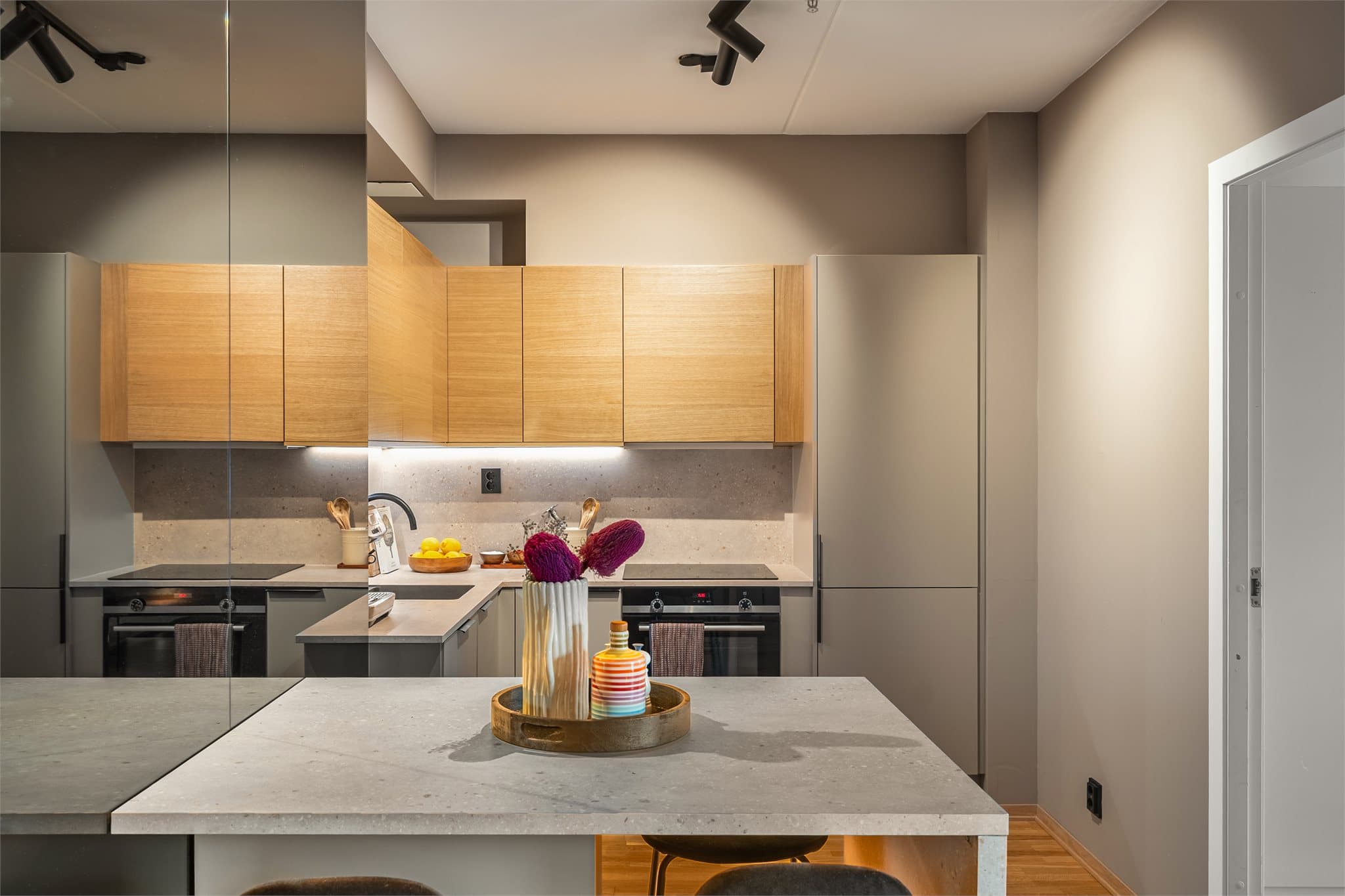 Leiligheten har et stilrent kjøkken med en praktisk benk som fungerer som en sosial sone og naturlig romdeler.