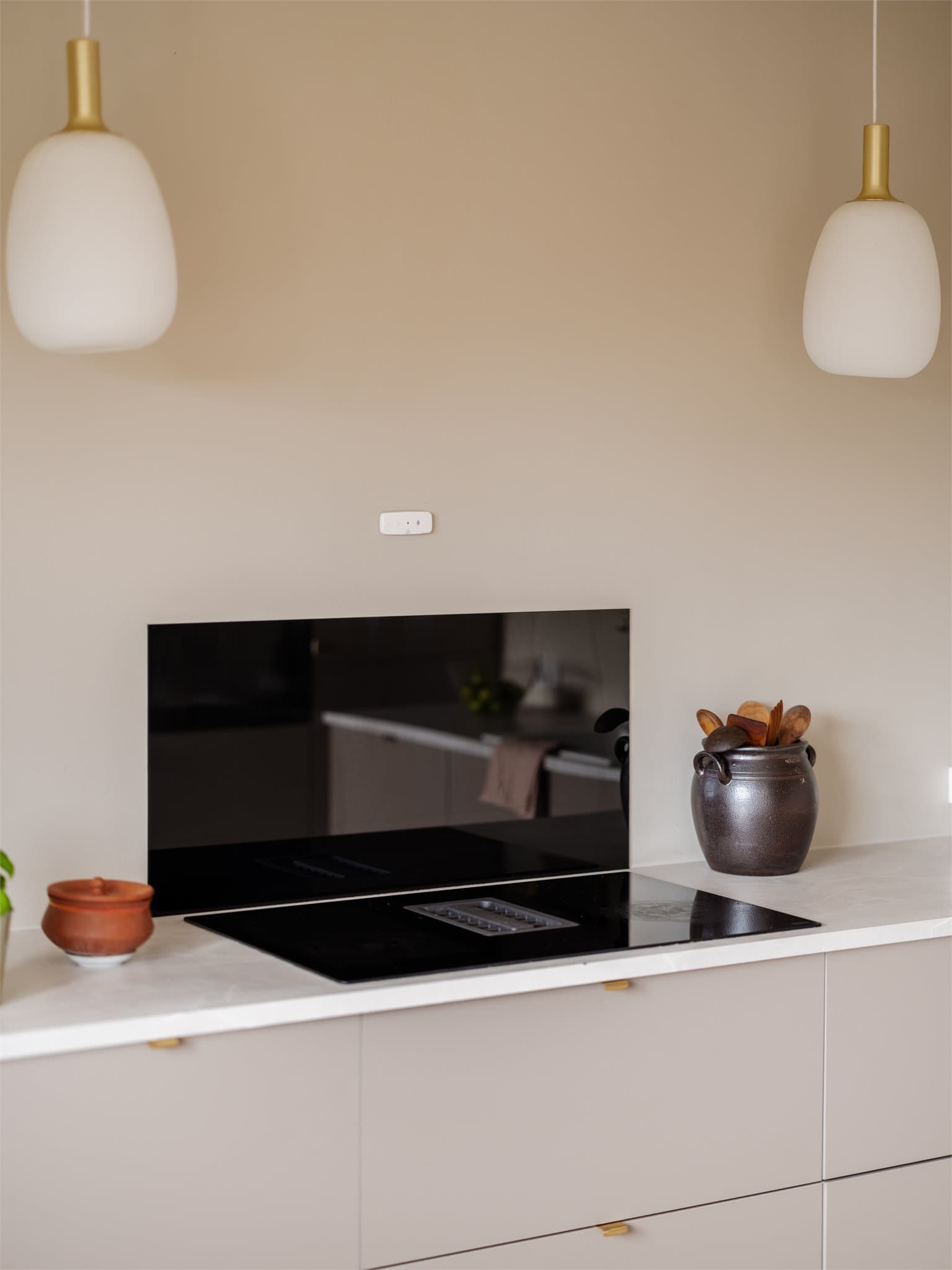 Induksjonsplatetopp med integrert ventilator og glassplate på vegg.