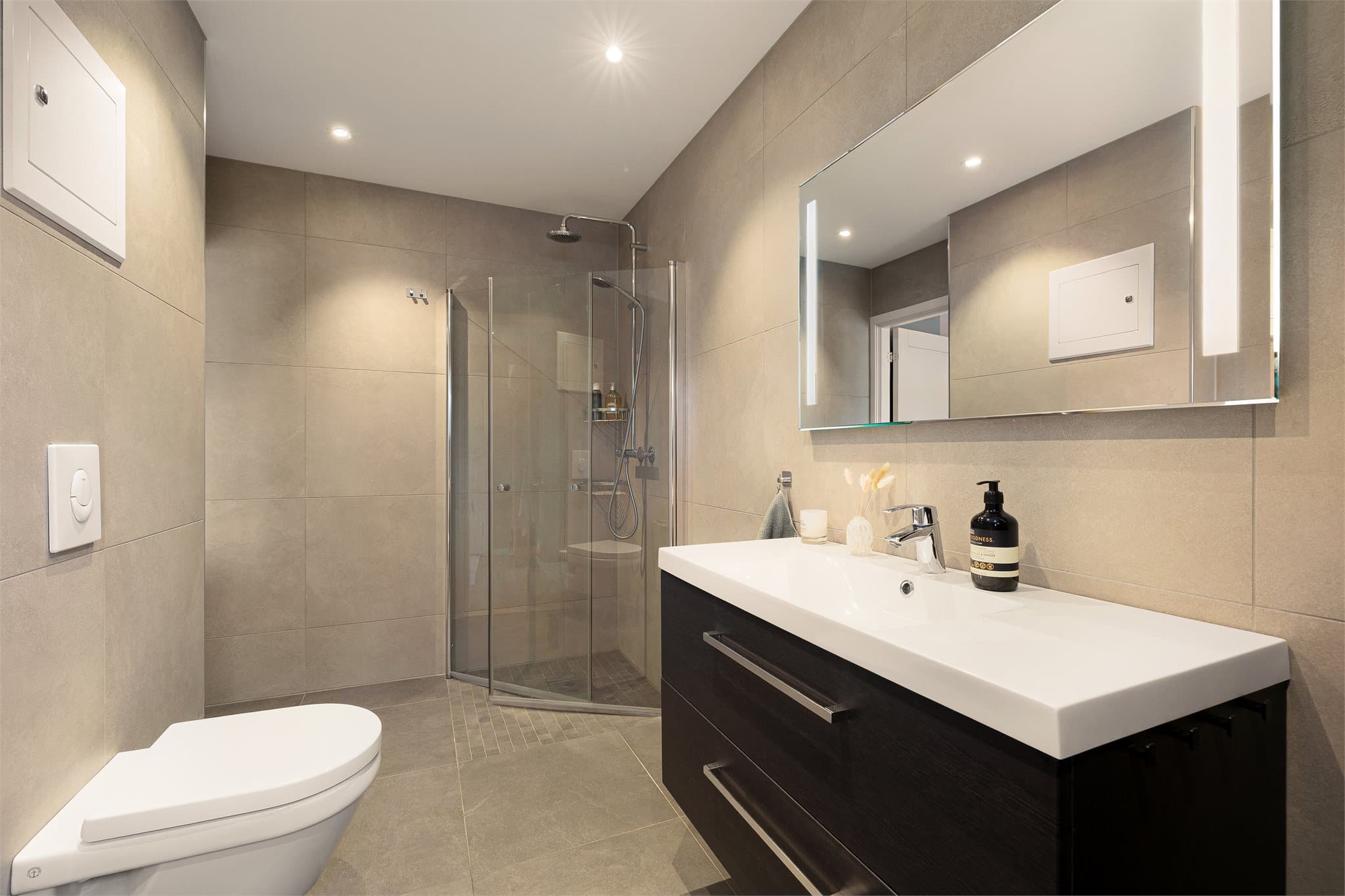 Et lekkert og delikat baderom med store fliser og downlights i himling.