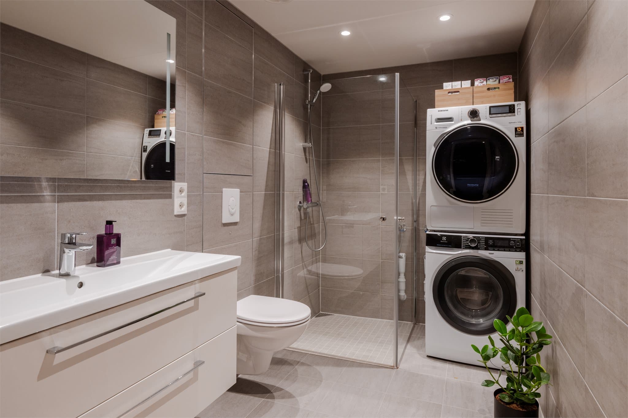 Lekkert, flislagt baderom med varme i gulvet og opplegg for vaskesøyle.