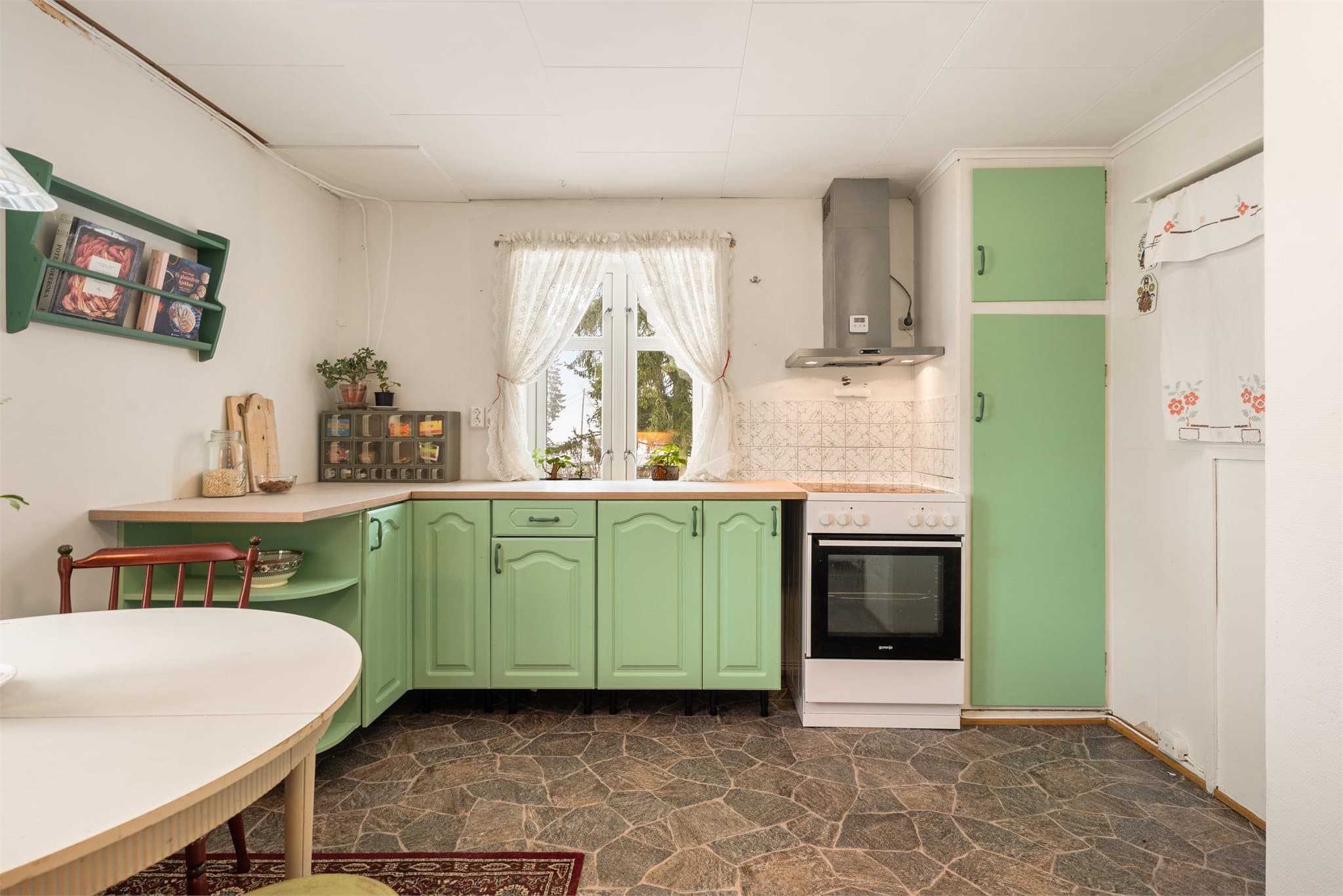 Den mintfargede kjøkkeninnredningen komplementerer husets sjarmerende detaljer og understreker boligens lune og hjemmekoselige atmosfære.