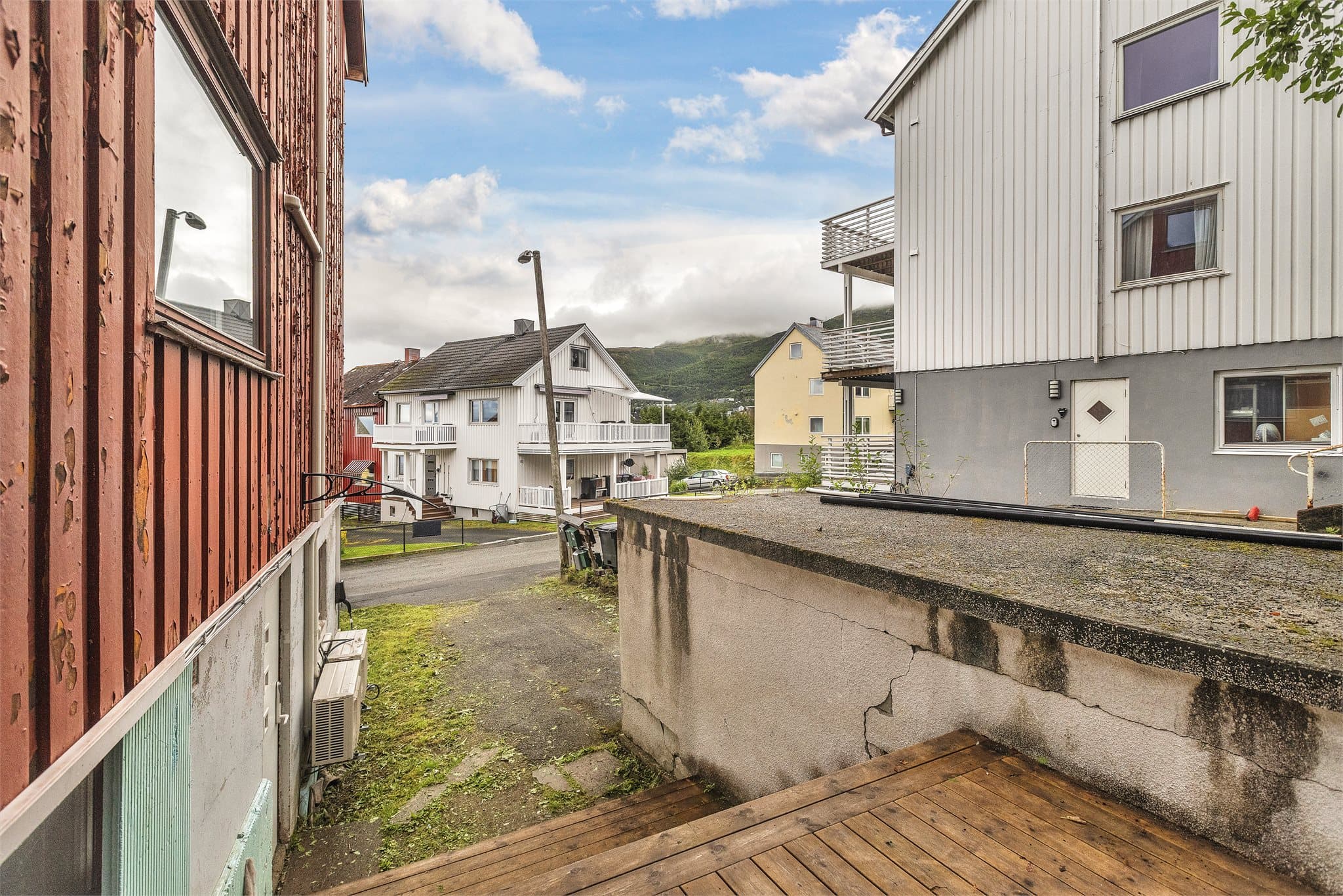 Utsikt mot nærområdet og fjellene, med frittstående betonggarasje foran tomten.